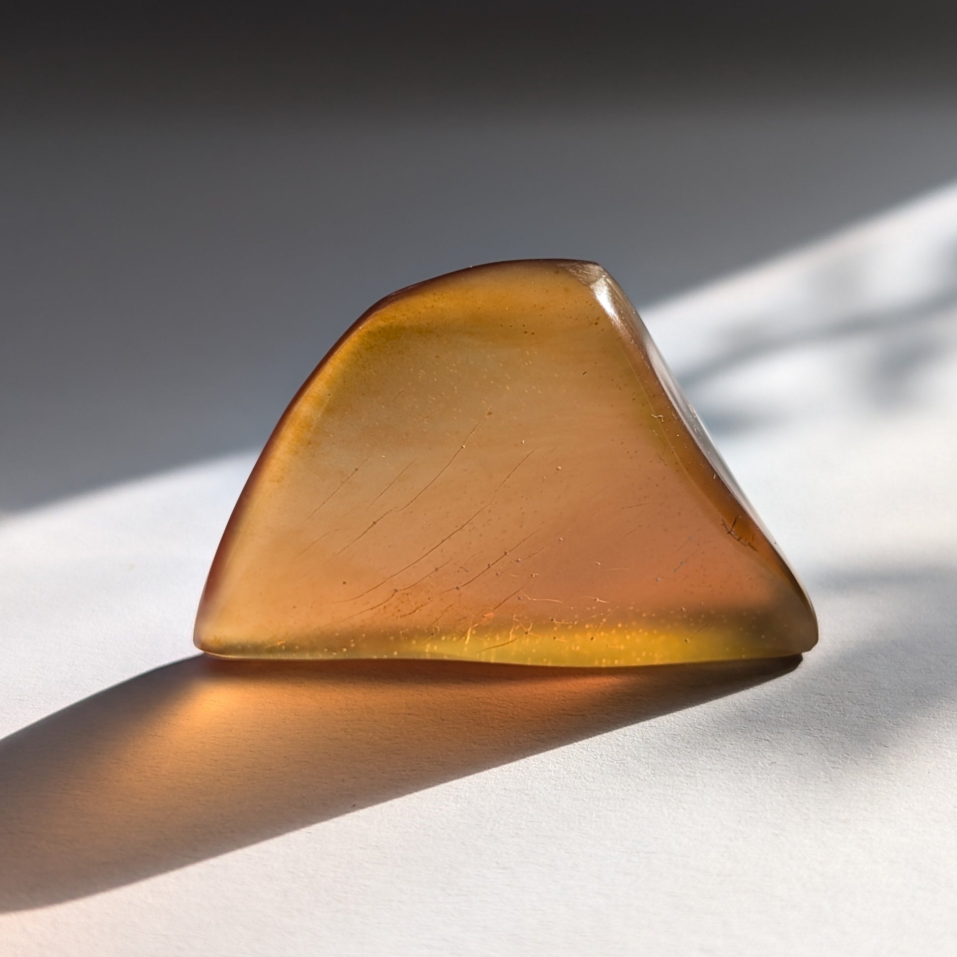 Ein polierter Bicolor-Bernstein 'Herz der Sommersonne' in natürlicher Freiform, der von Cognac-braun zu leuchtendem Sonnengelb übergeht.
