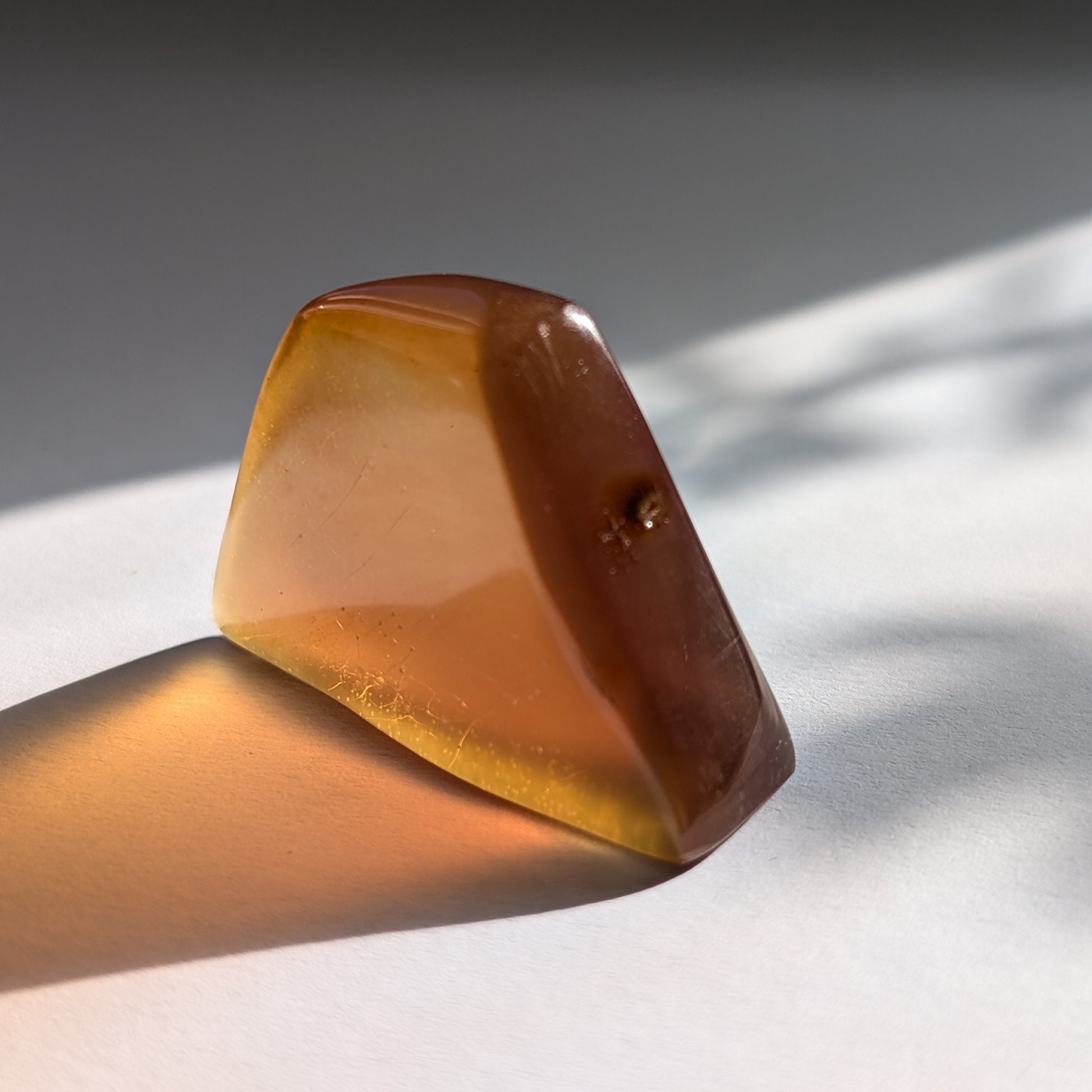 Ein polierter Bicolor-Bernstein 'Herz der Sommersonne' in natürlicher Freiform, der von Cognac-braun zu leuchtendem Sonnengelb übergeht.