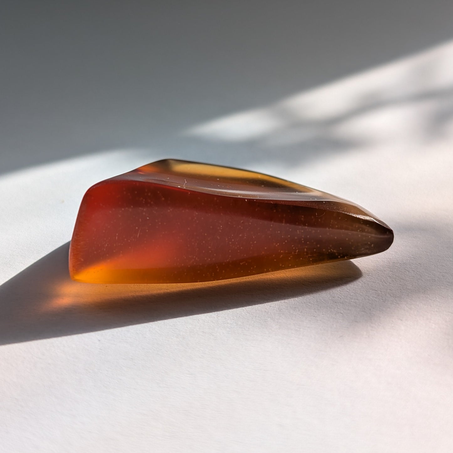 Ein polierter Bicolor-Bernstein 'Herz der Sommersonne' in natürlicher Freiform, der von Cognac-braun zu leuchtendem Sonnengelb übergeht.