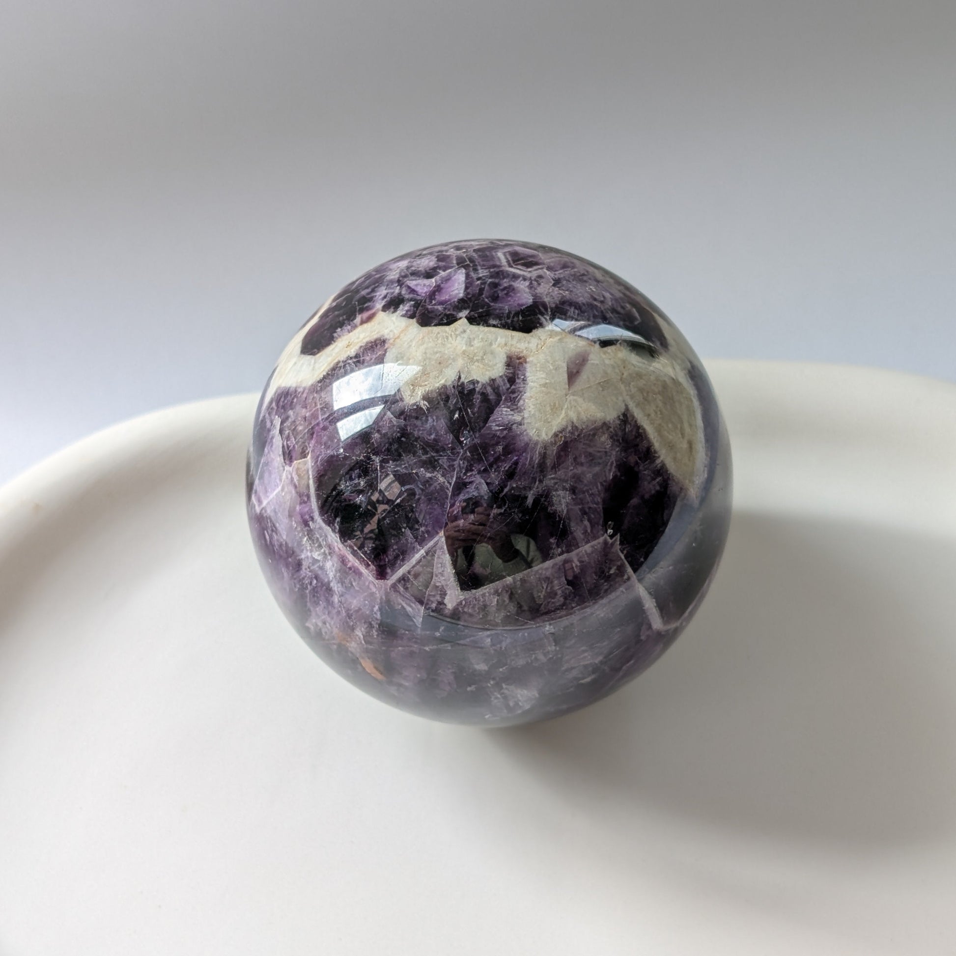 Eine 468g schwere, polierte Kugel aus Chevron Amethyst 'Das Orakel der Seele' mit markanten violetten und weißen Bändern.