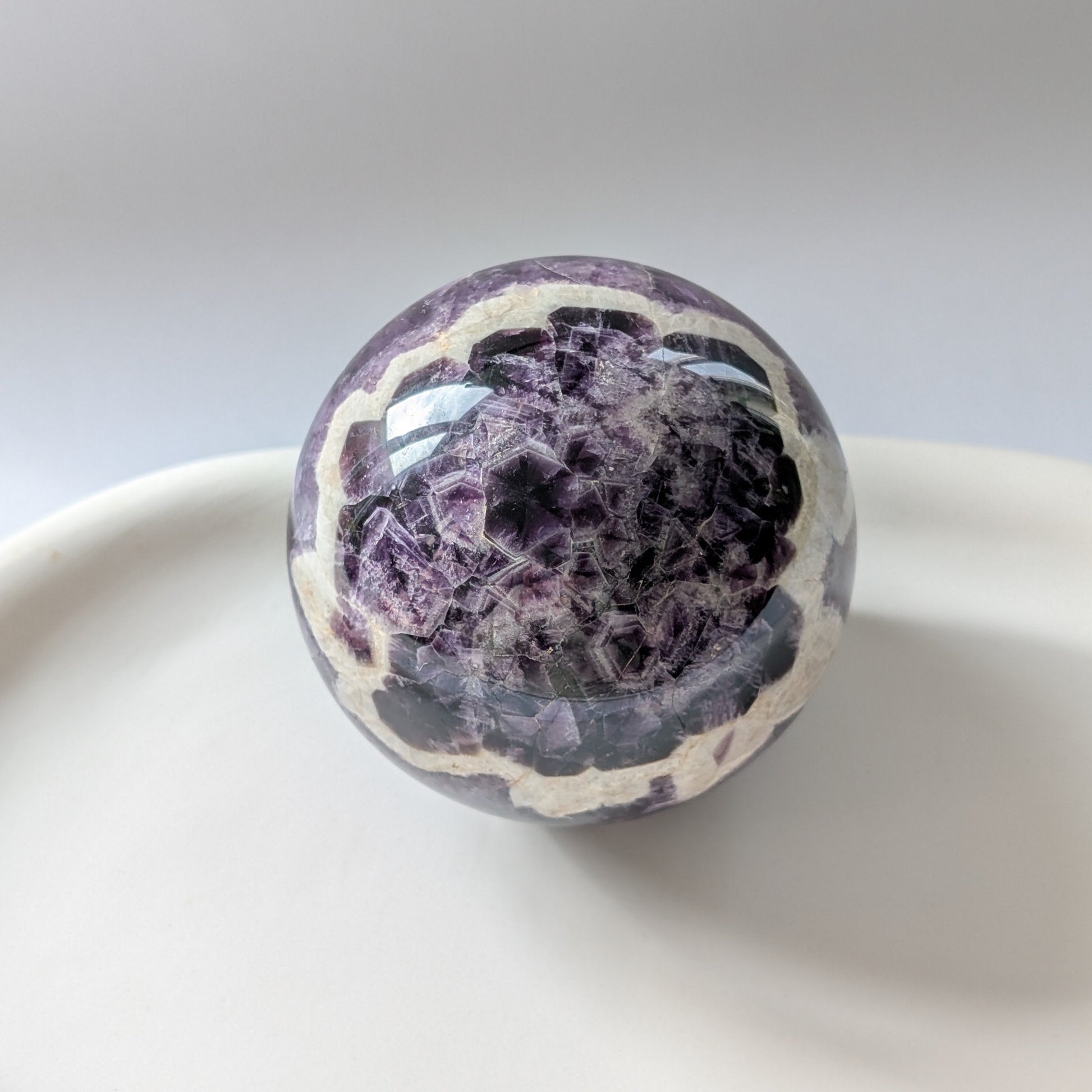 Eine 468g schwere, polierte Kugel aus Chevron Amethyst 'Das Orakel der Seele' mit markanten violetten und weißen Bändern.