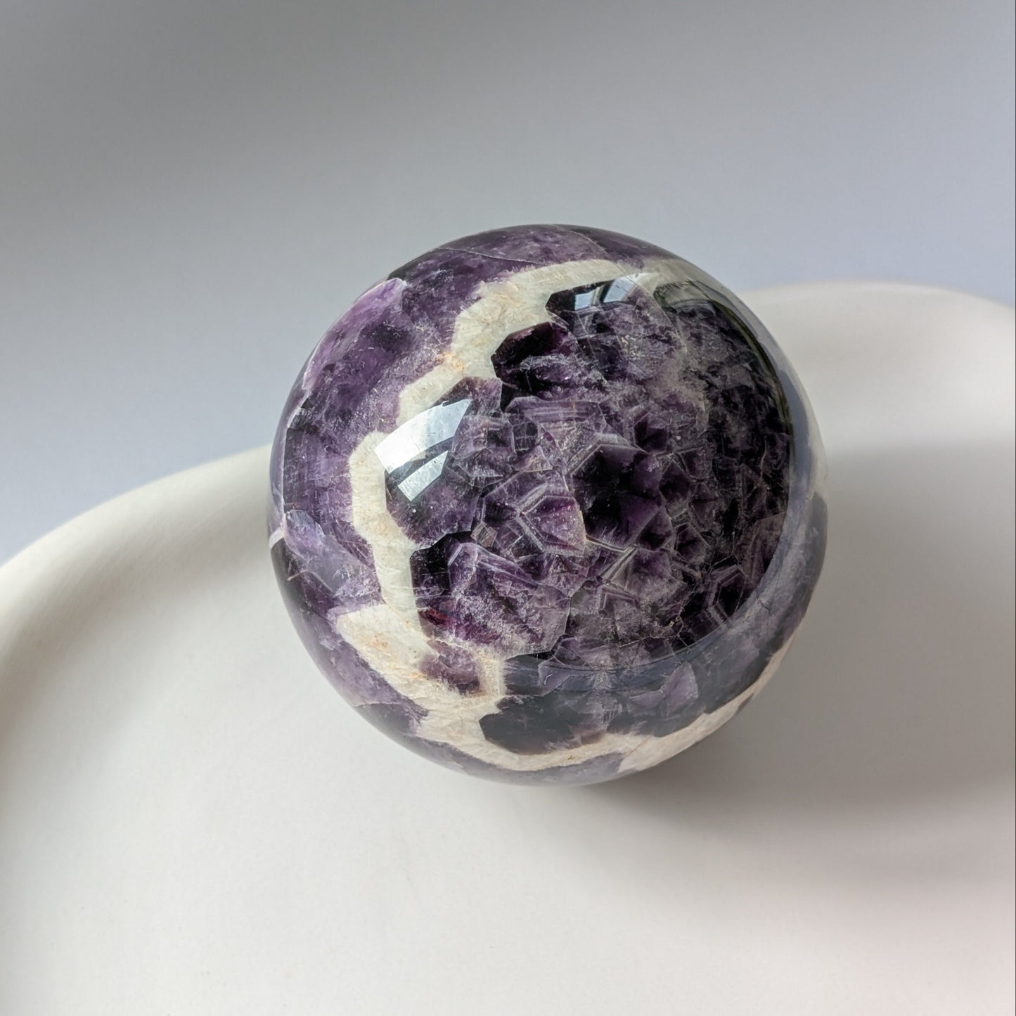 Eine 468g schwere, polierte Kugel aus Chevron Amethyst 'Das Orakel der Seele' mit markanten violetten und weißen Bändern.