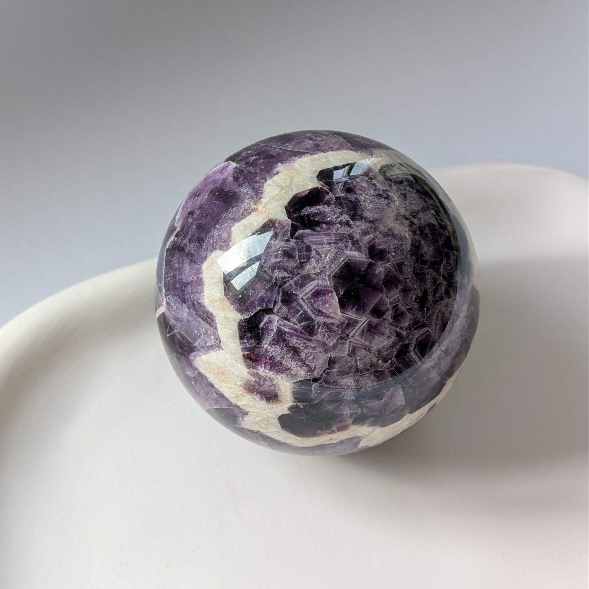 Eine 468g schwere, polierte Kugel aus Chevron Amethyst 'Das Orakel der Seele' mit markanten violetten und weißen Bändern.