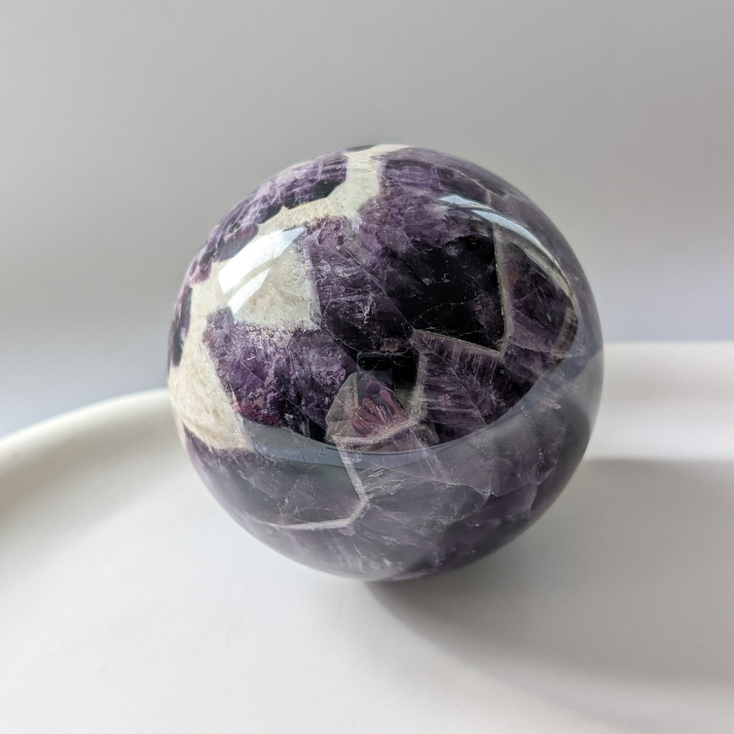 Eine 468g schwere, polierte Kugel aus Chevron Amethyst 'Das Orakel der Seele' mit markanten violetten und weißen Bändern.