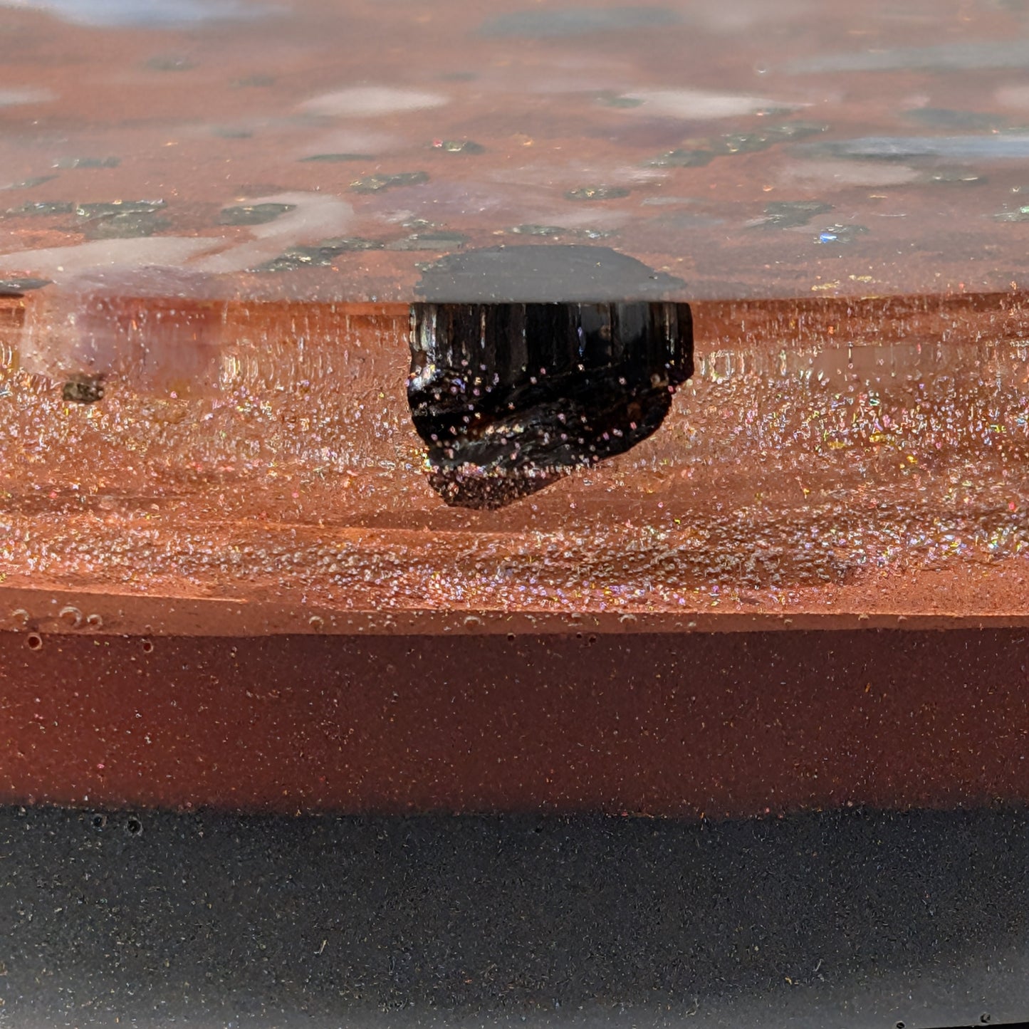 Eine große, runde Orgonit Energetisierungsplatte (17cm) 'Quelle der Kraft' mit sichtbaren Kristallen wie Kyanit und Pyrit in einer rötlichen Matrix.