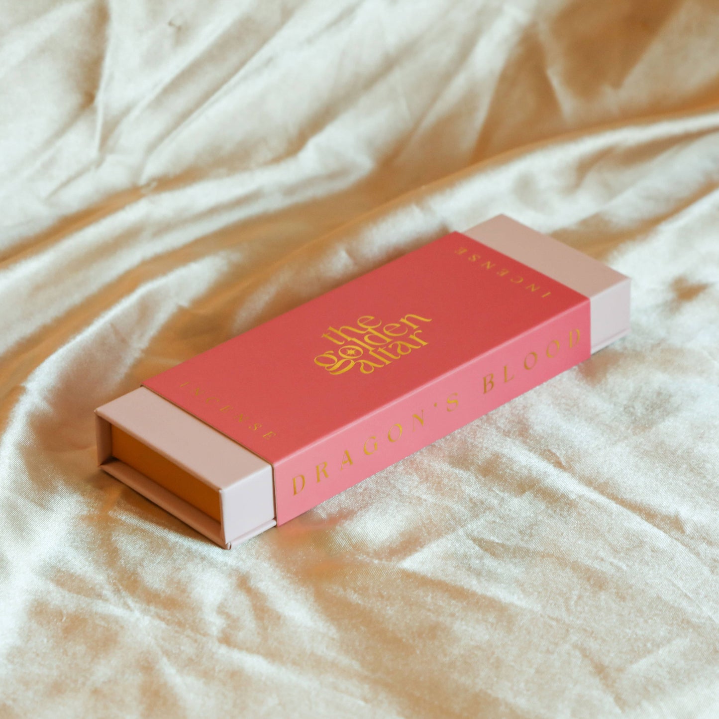 Eine leuchtend pinke Box von The Golden Altar mit 30 roten Drachenblut Räucherstäbchen, die daneben liegen.