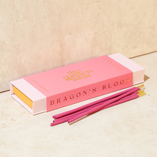 Eine leuchtend pinke Box von The Golden Altar mit 30 roten Drachenblut Räucherstäbchen, die daneben liegen.