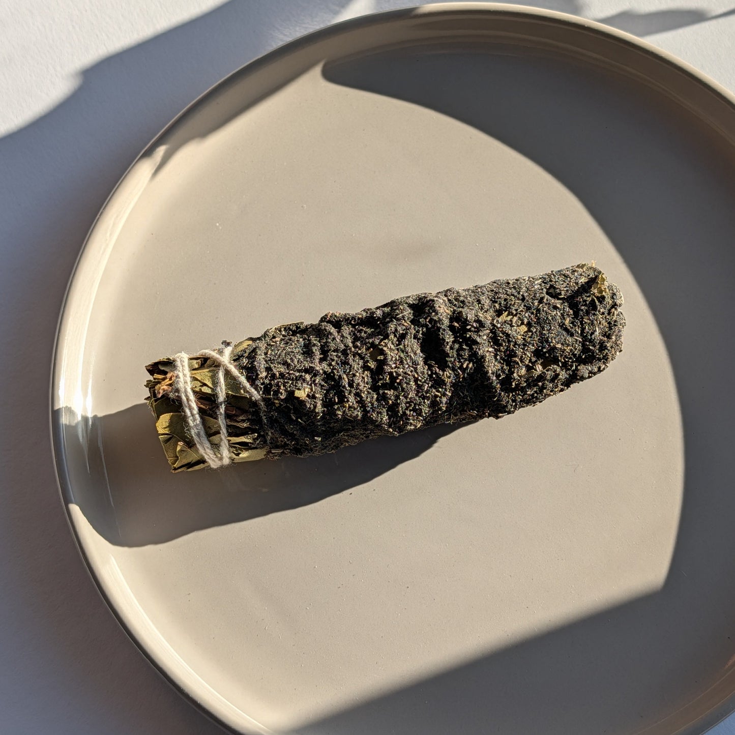 Einzelnes handgebundenes Räucherbündel mit Storax und Kampfer auf einem Keramikteller