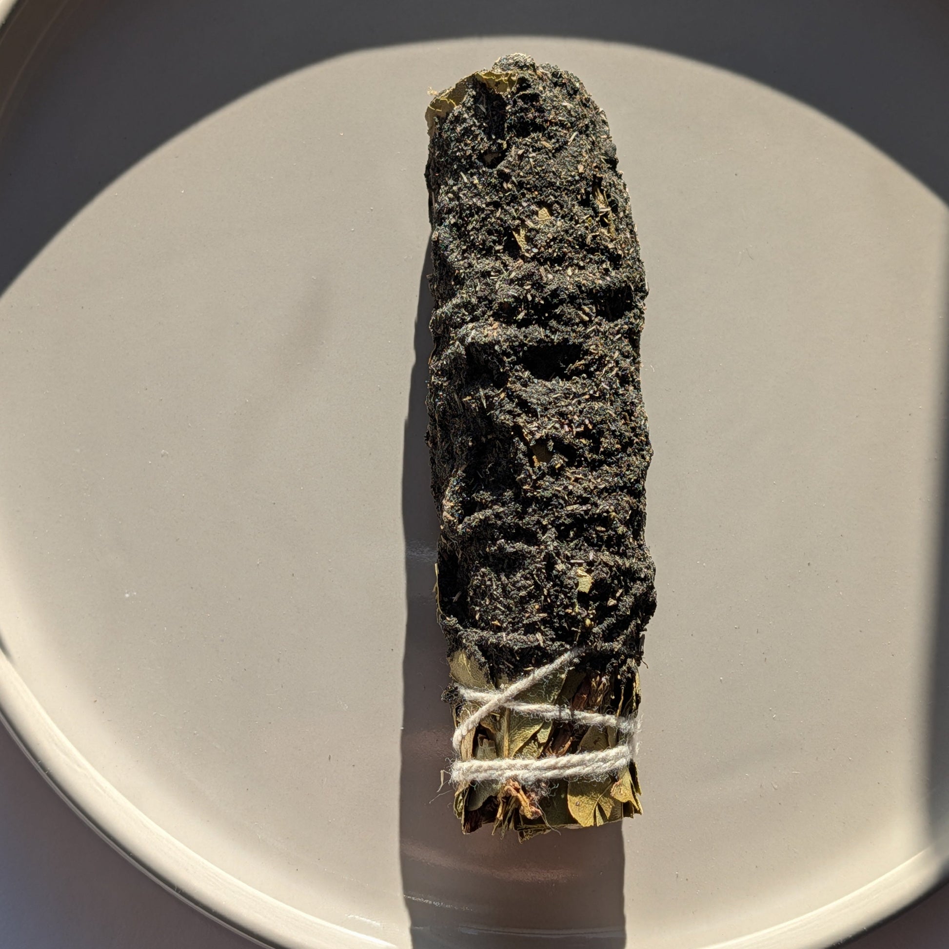 Einzelnes handgebundenes Räucherbündel mit Storax und Kampfer auf einem Keramikteller