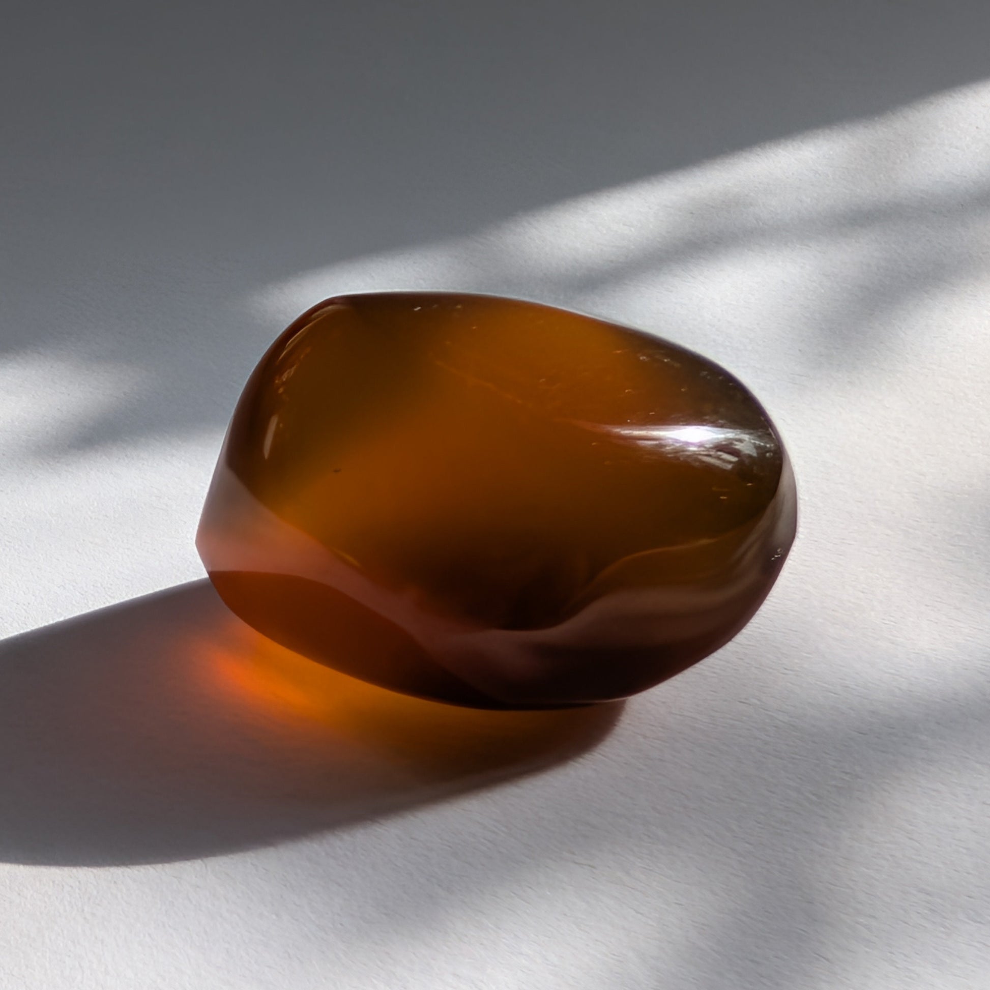 Eleganter Bicolor-Bernstein 'Der Seelenwärmer' in natürlicher Freiform, der sanft von tiefem Rot in einen goldenen Cognac-Ton übergeht.