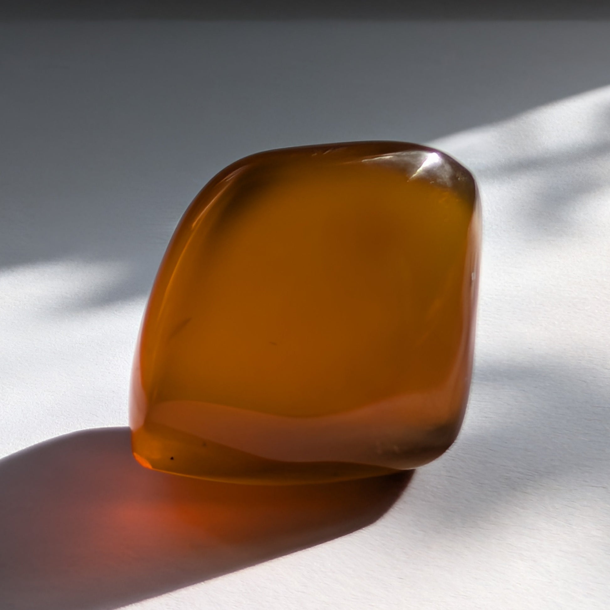 Eleganter Bicolor-Bernstein 'Der Seelenwärmer' in natürlicher Freiform, der sanft von tiefem Rot in einen goldenen Cognac-Ton übergeht.