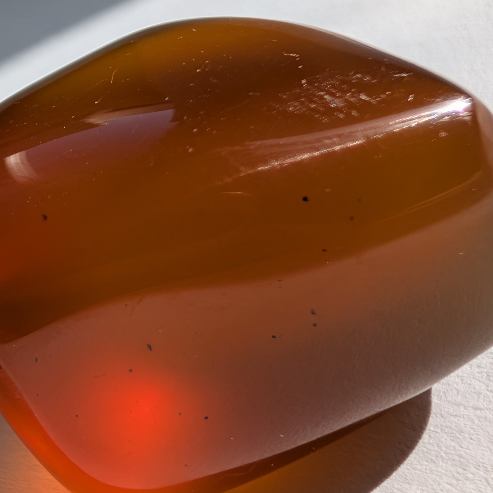 Eleganter Bicolor-Bernstein 'Der Seelenwärmer' in natürlicher Freiform, der sanft von tiefem Rot in einen goldenen Cognac-Ton übergeht.