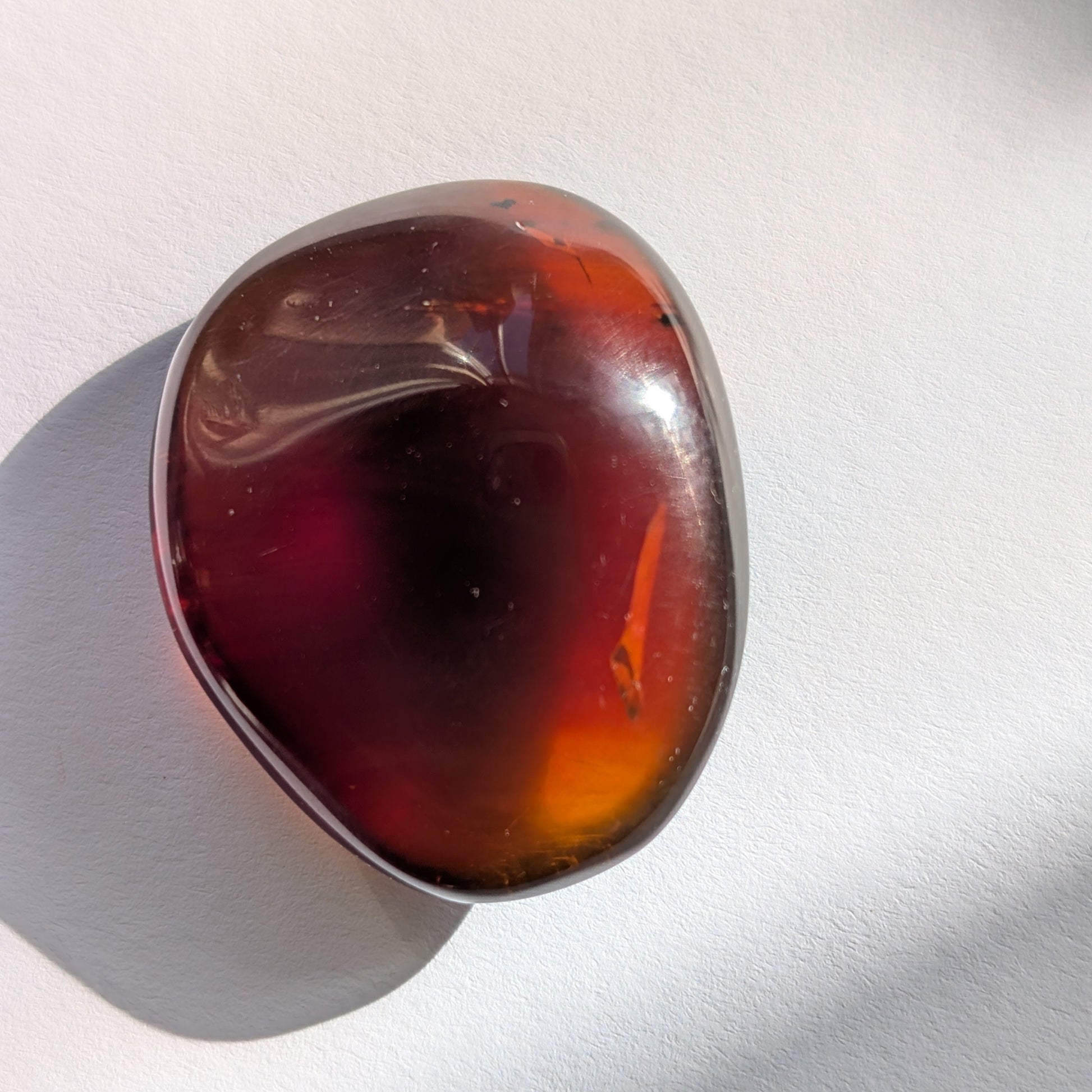 Eleganter Bicolor-Bernstein 'Herz der Dämmerung' in natürlicher Freiform, der sanft von tiefem Rot in einen goldenen Cognac-Ton übergeht.