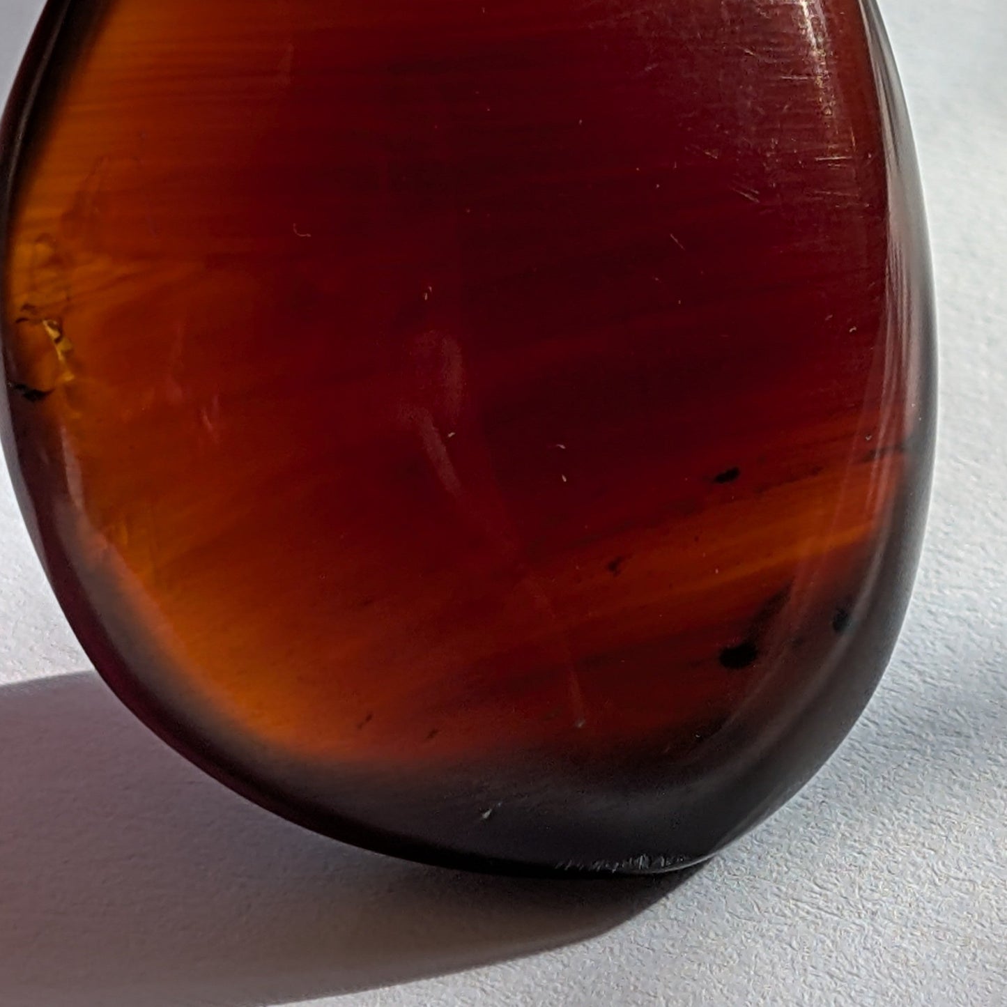 Eleganter Bicolor-Bernstein 'Herz der Dämmerung' in natürlicher Freiform, der sanft von tiefem Rot in einen goldenen Cognac-Ton übergeht.