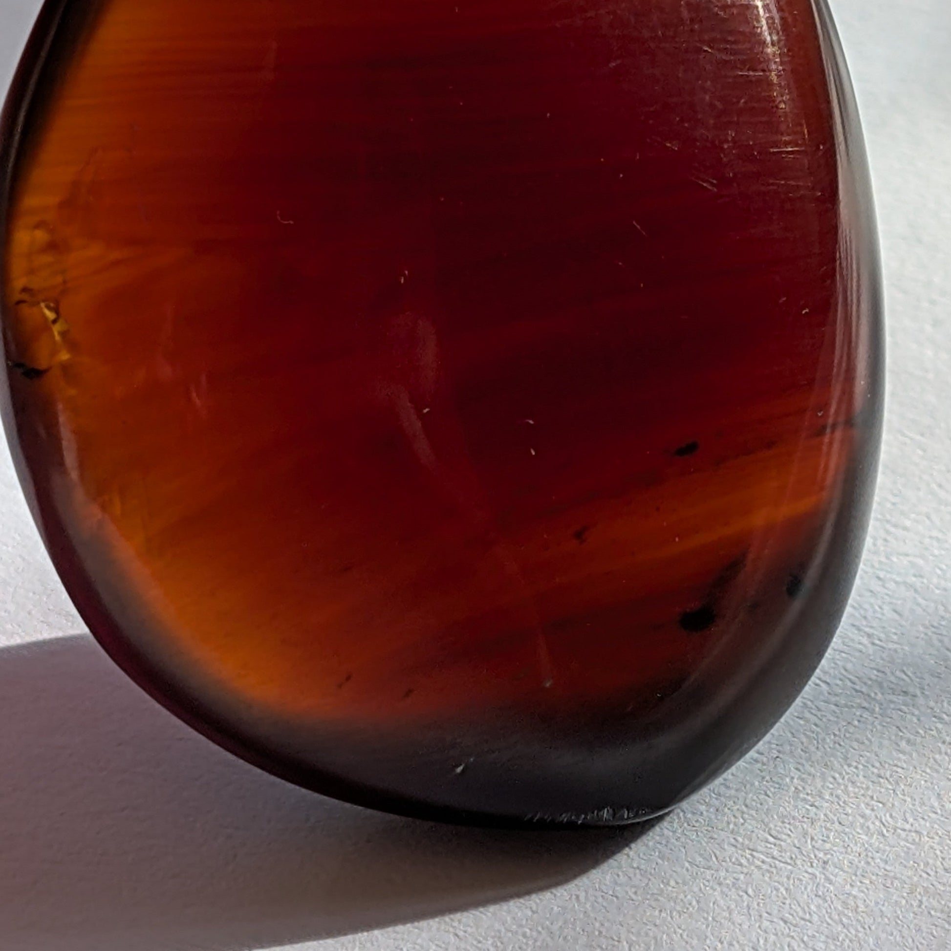 Eleganter Bicolor-Bernstein 'Herz der Dämmerung' in natürlicher Freiform, der sanft von tiefem Rot in einen goldenen Cognac-Ton übergeht.