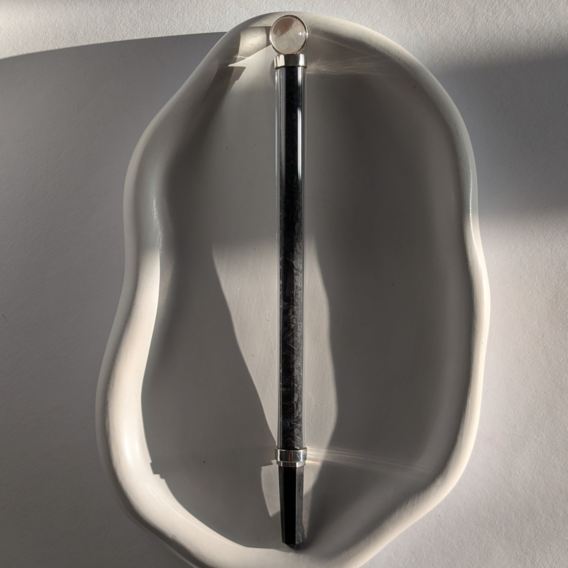Eleganter Generatorstab mit Schungit-Füllung, Quarzkugel und schwarzer Spitze in hellem Licht.