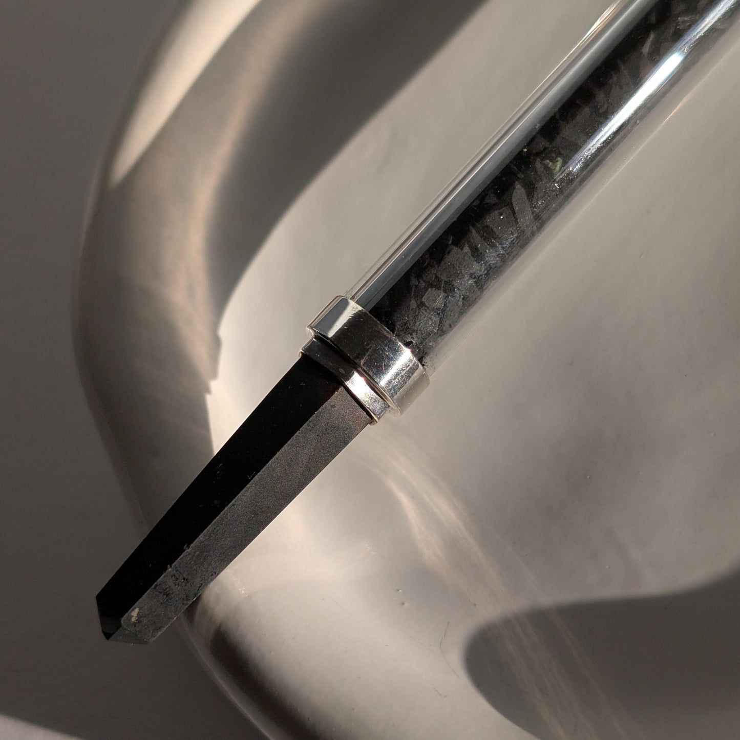 Eleganter Generatorstab mit Schungit-Füllung, Quarzkugel und schwarzer Spitze in hellem Licht.