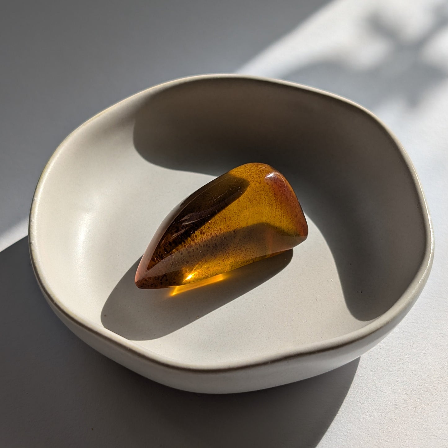 Eleganter, von Natur aus tropfenförmiger Bicolor-Bernstein 'Die Träne der Sonne', der von tiefem Kirschrot zu leuchtendem Gold schimmert.