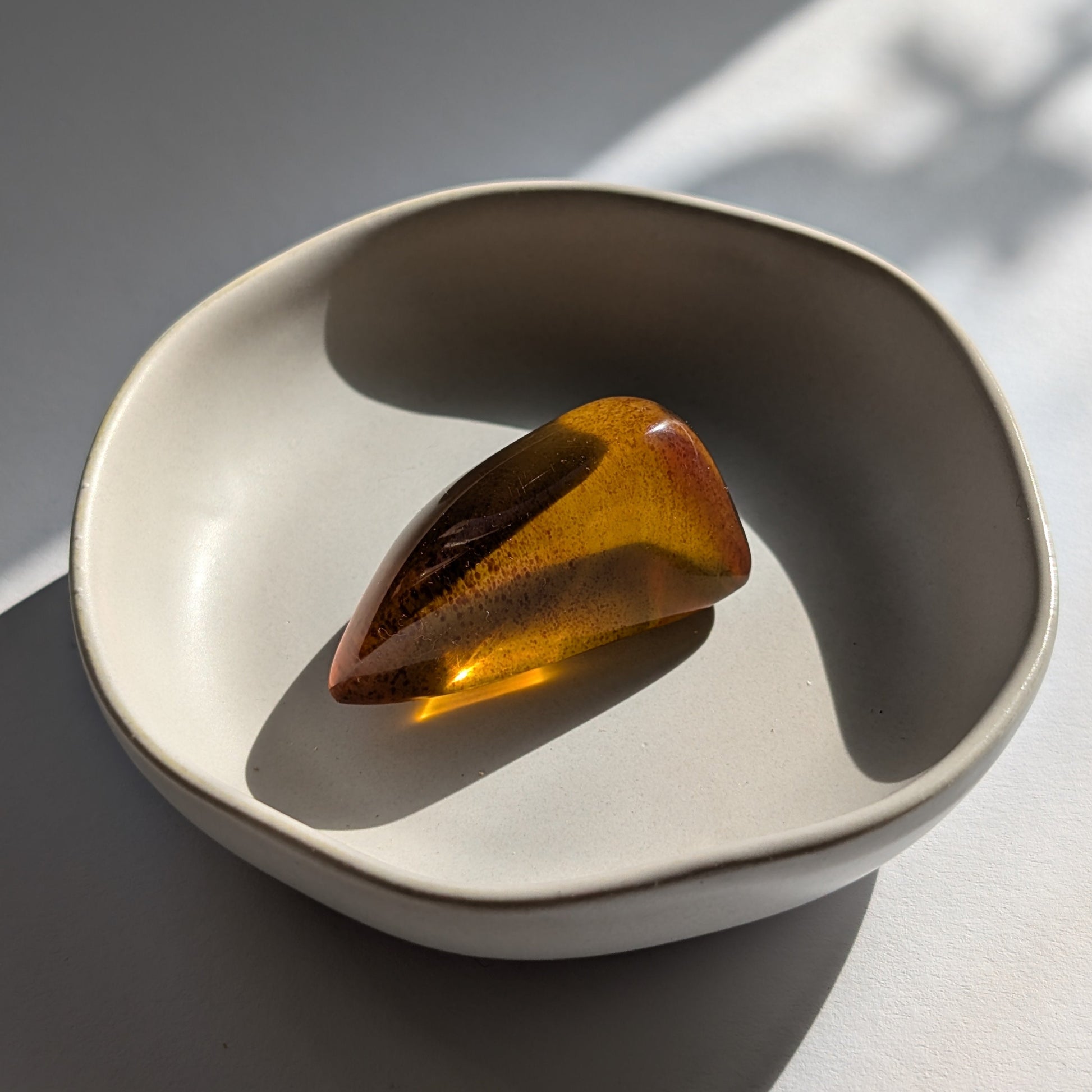 Eleganter, von Natur aus tropfenförmiger Bicolor-Bernstein 'Die Träne der Sonne', der von tiefem Kirschrot zu leuchtendem Gold schimmert.