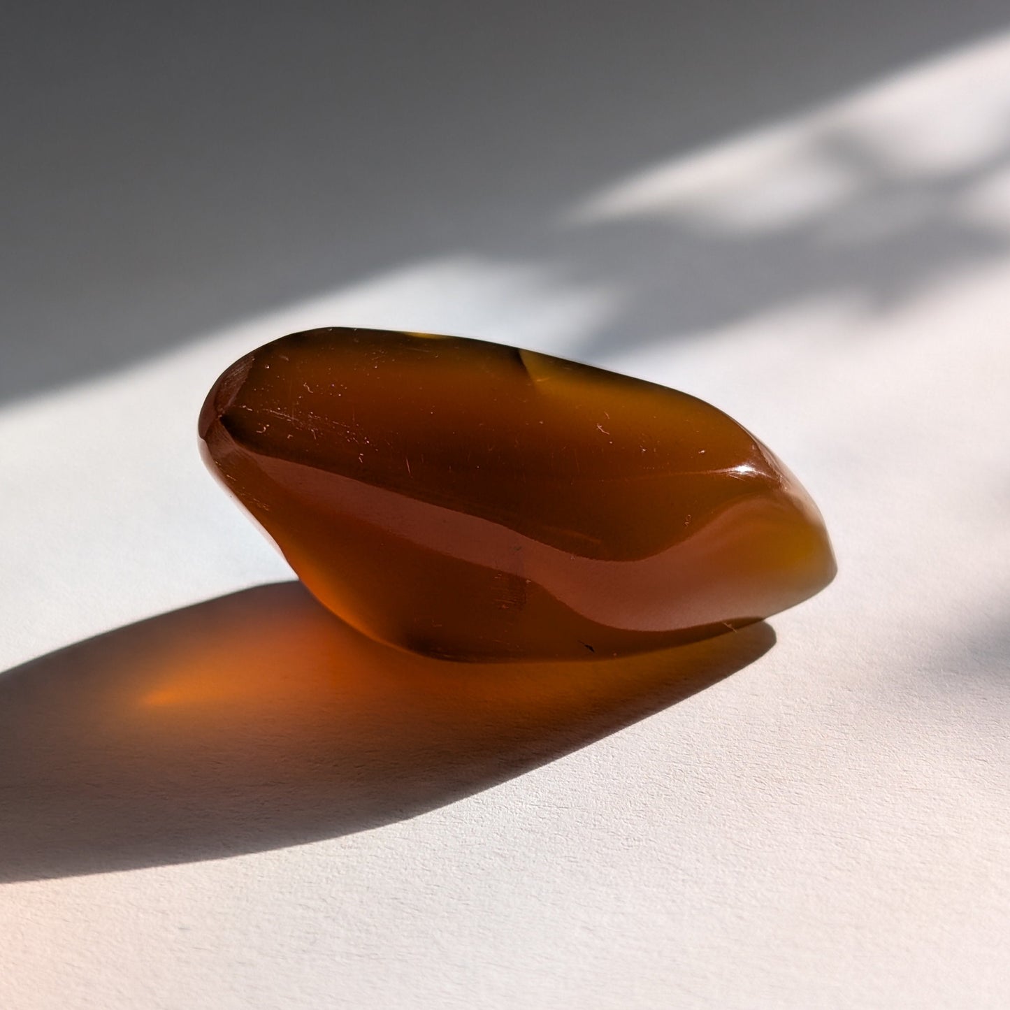 Eleganter, von Natur aus tropfenförmiger Bicolor-Bernstein 'Die Träne der Sonne', der von tiefem Kirschrot zu leuchtendem Gold schimmert.