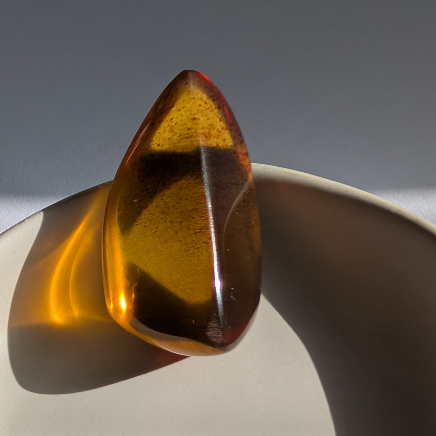 Eleganter, von Natur aus tropfenförmiger Bicolor-Bernstein 'Die Träne der Sonne', der von tiefem Kirschrot zu leuchtendem Gold schimmert.