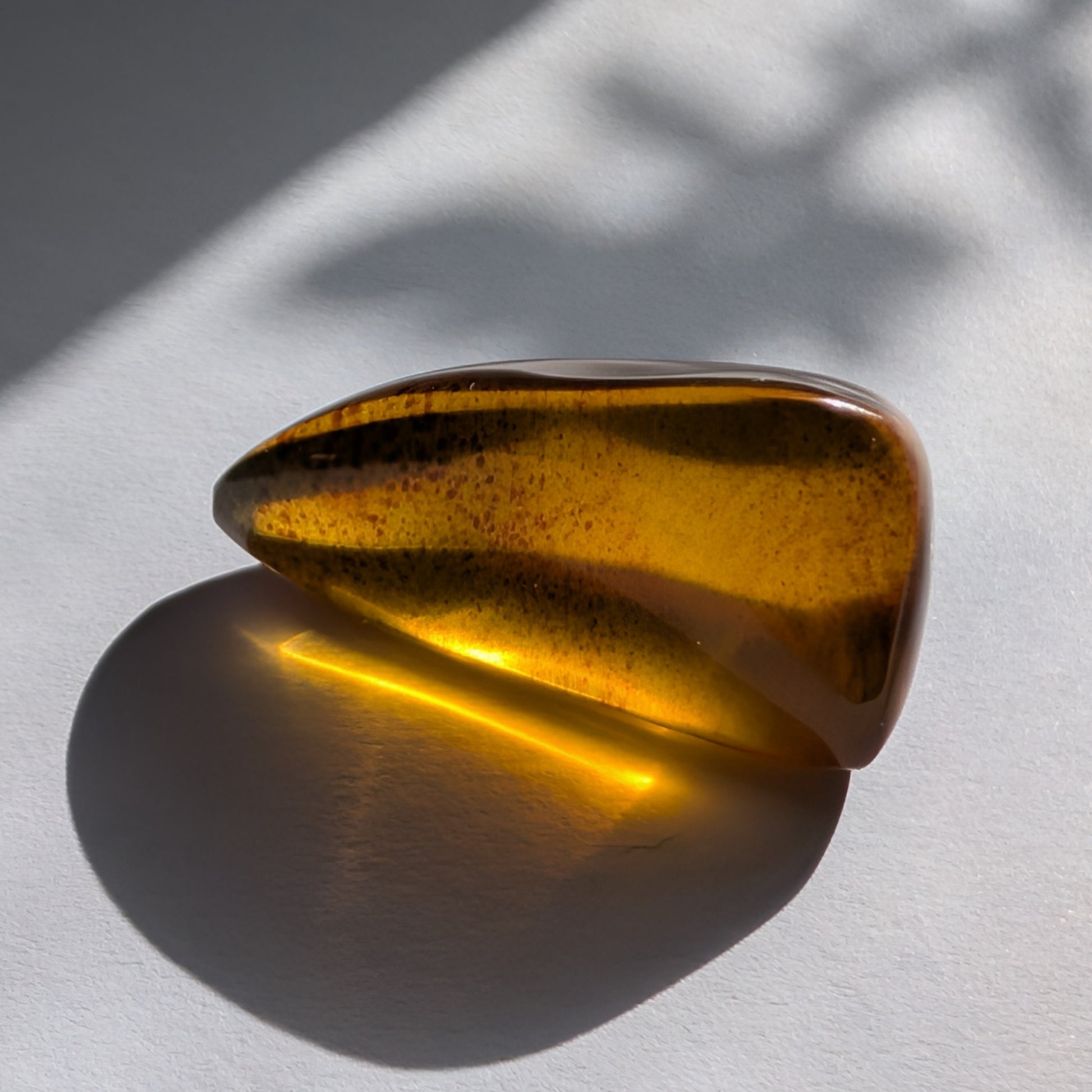 Eleganter, von Natur aus tropfenförmiger Bicolor-Bernstein 'Die Träne der Sonne', der von tiefem Kirschrot zu leuchtendem Gold schimmert.
