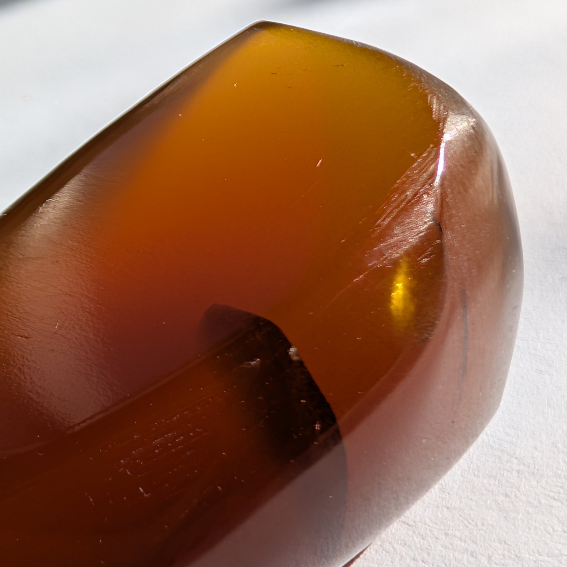 Eleganter, von Natur aus tropfenförmiger Bicolor-Bernstein 'Die Träne der Sonne', der von tiefem Kirschrot zu leuchtendem Gold schimmert.