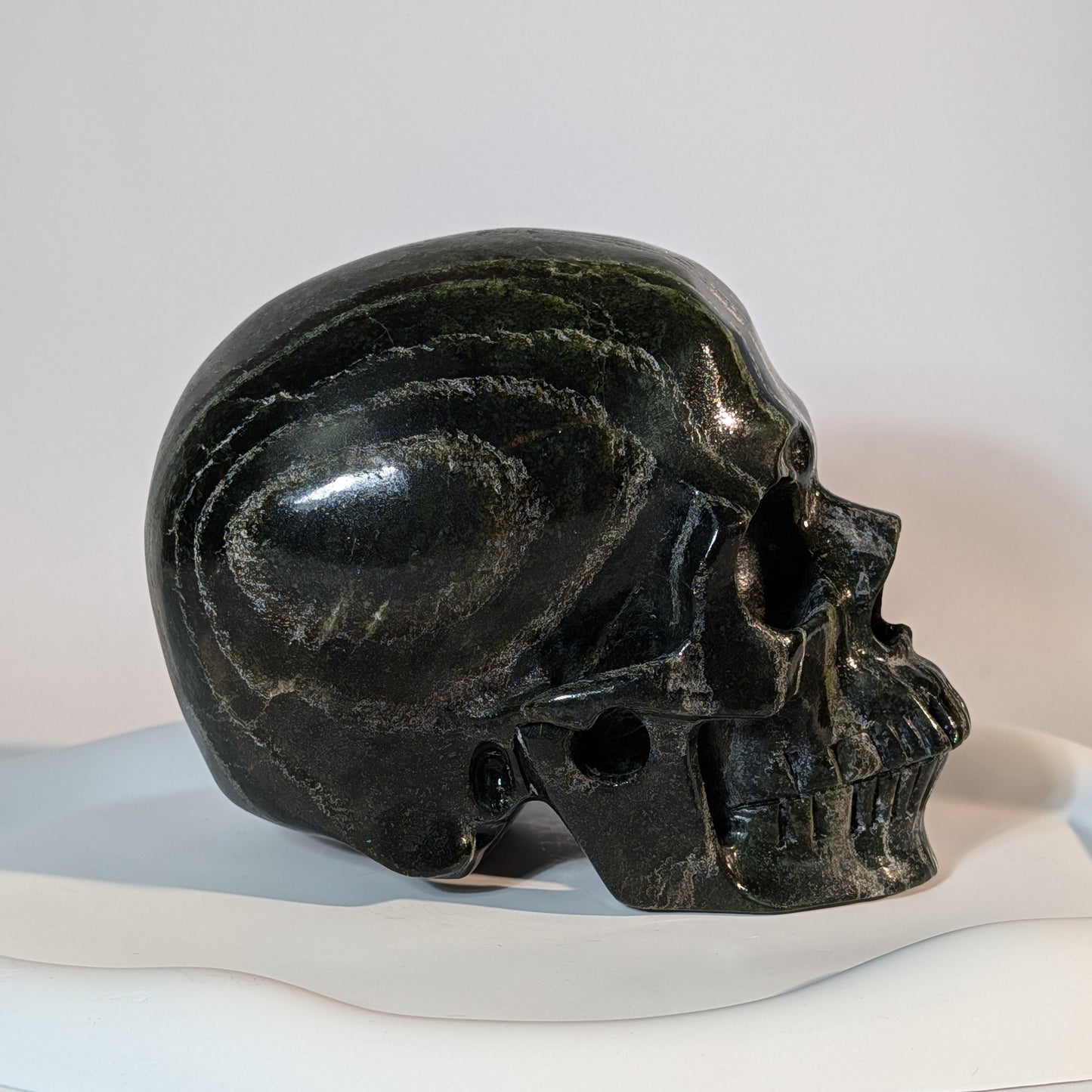 Gewaltiger Kristallschädel Tantaro aus dunkelrotem und braunem Serpentin, gezeichnet von scharfen, dunklen Gesteinsadern