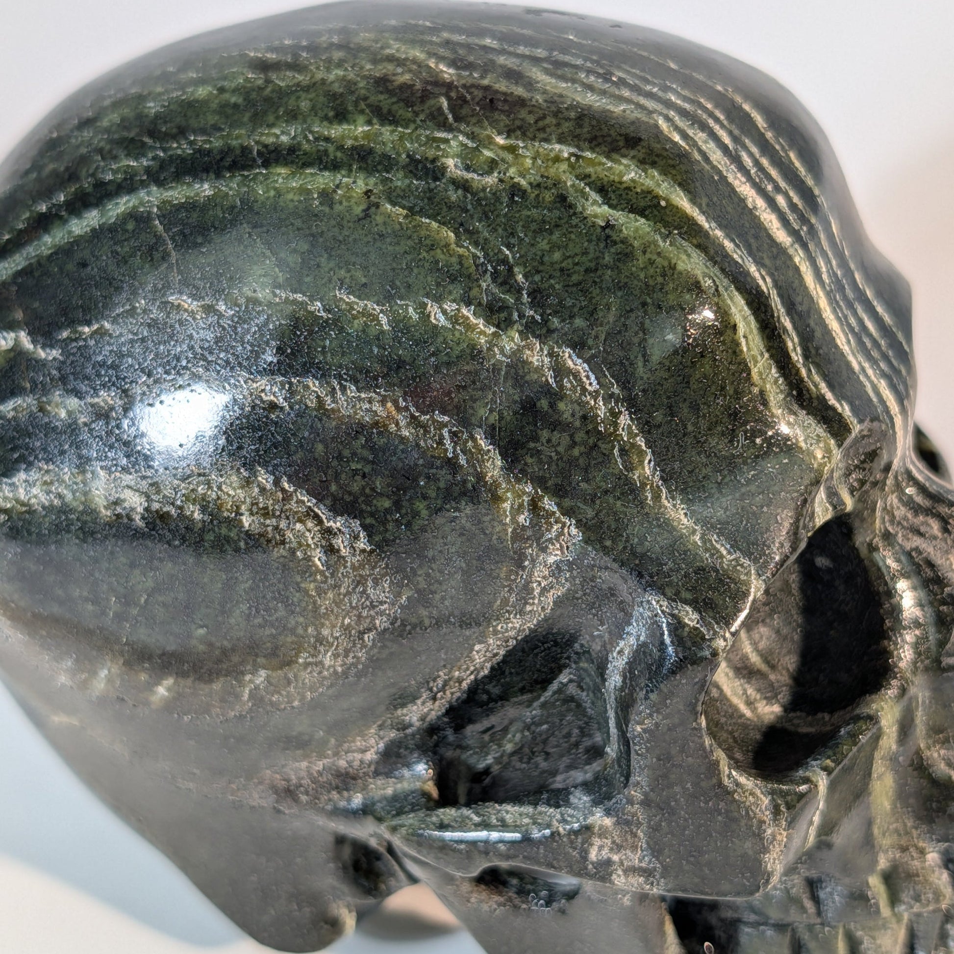 Gewaltiger Kristallschädel Tantaro aus dunkelrotem und braunem Serpentin, gezeichnet von scharfen, dunklen Gesteinsadern