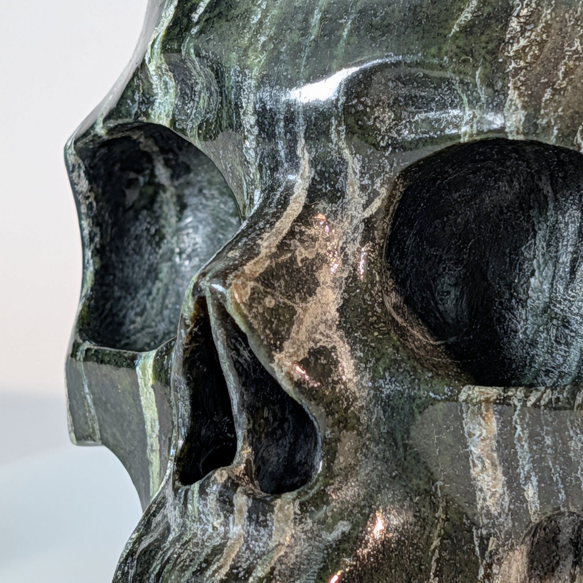 Gewaltiger Kristallschädel Tantaro aus dunklem Serpentin, durchzogen von auffälligen, leuchtend grünen Gesteinsadern.