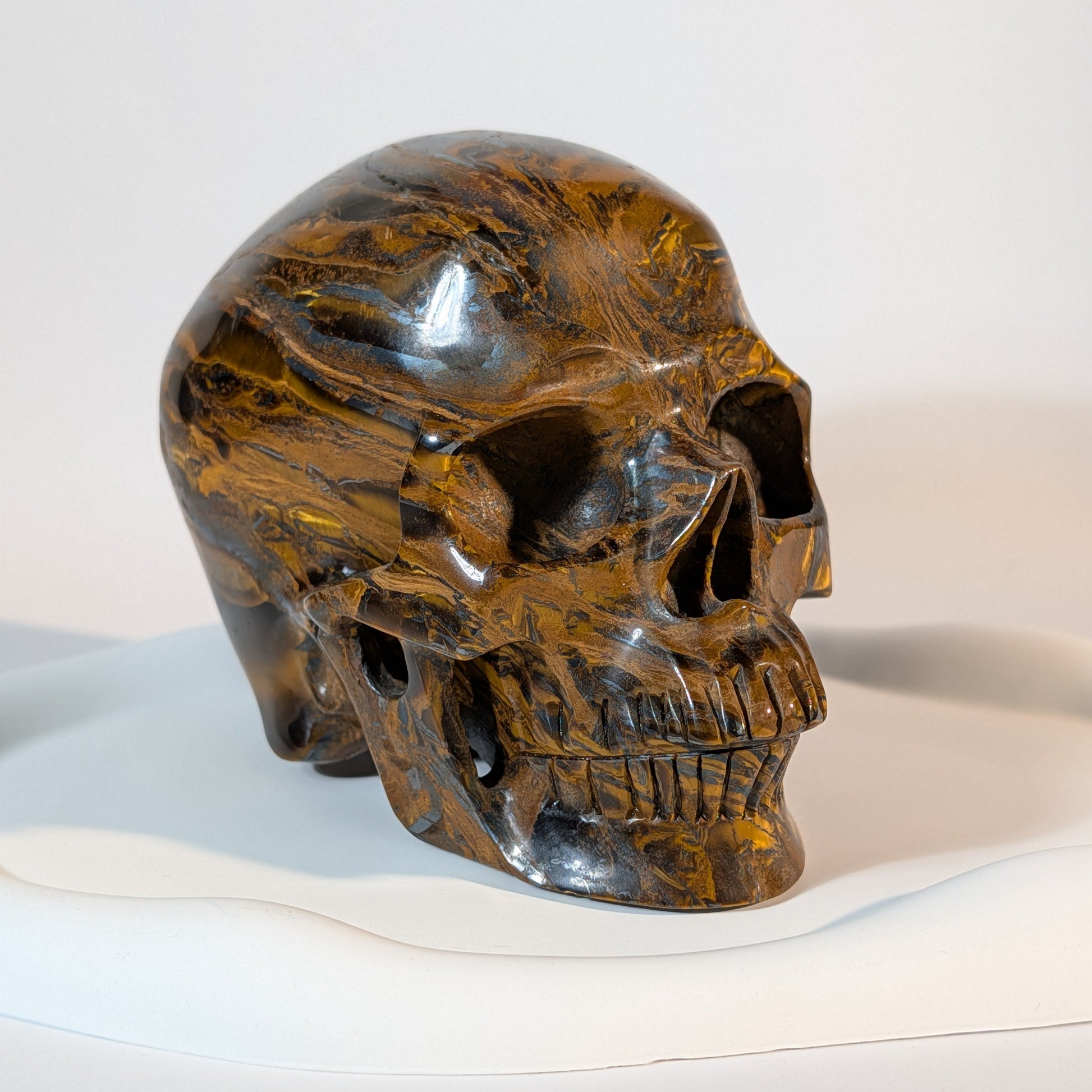 Gigantischer Kristallschädel aus Tigereisen, gezeichnet von markanten Bändern aus goldenem Tigerauge, metallischem Hämatit und rotem Jaspis