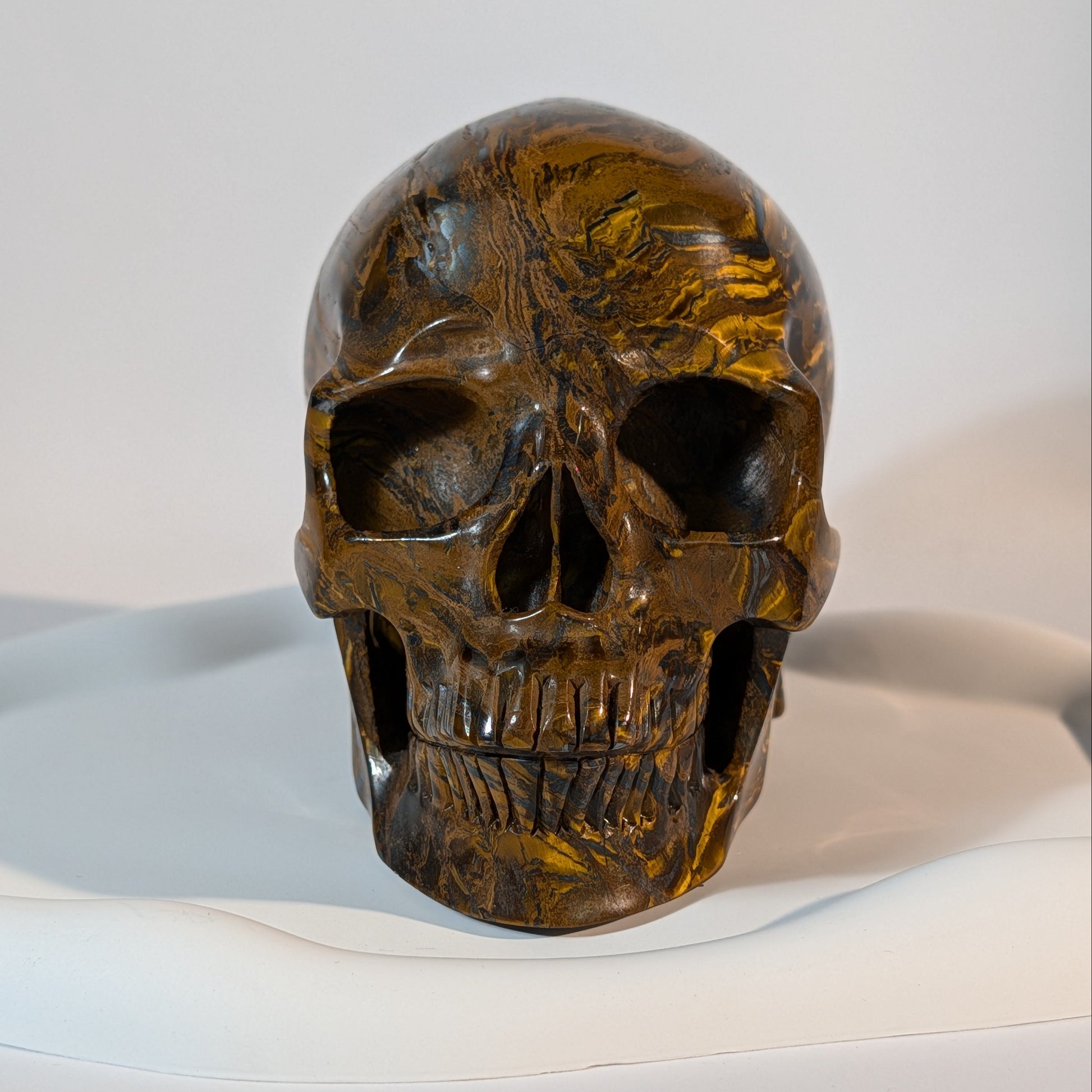 Gigantischer Kristallschädel, gezeichnet von markanten, zweifarbigen Bändern aus goldenem Tigerauge und silbrig-metallischem Hämatit.