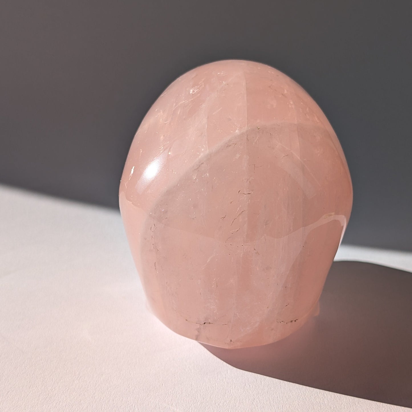 Großer Kristallschädel (1.16kg) aus sanft leuchtendem Rosenquarz im Seitenprofil.