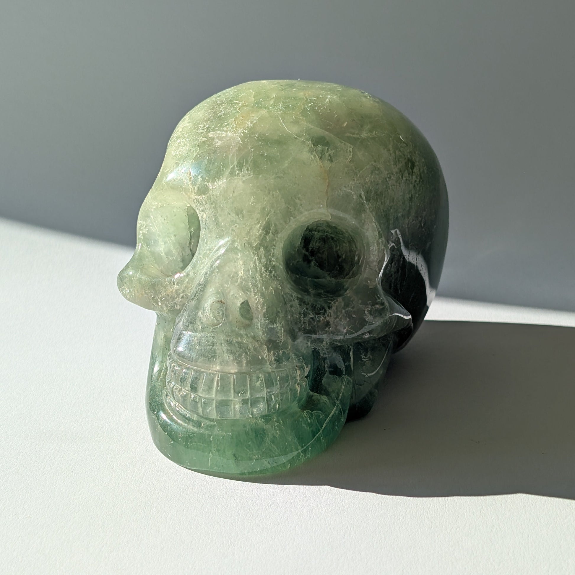 Großer Kristallschädel "Gulkar" (fast 2kg) aus leuchtend grünem Fluorit, seitlich beleuchtet.