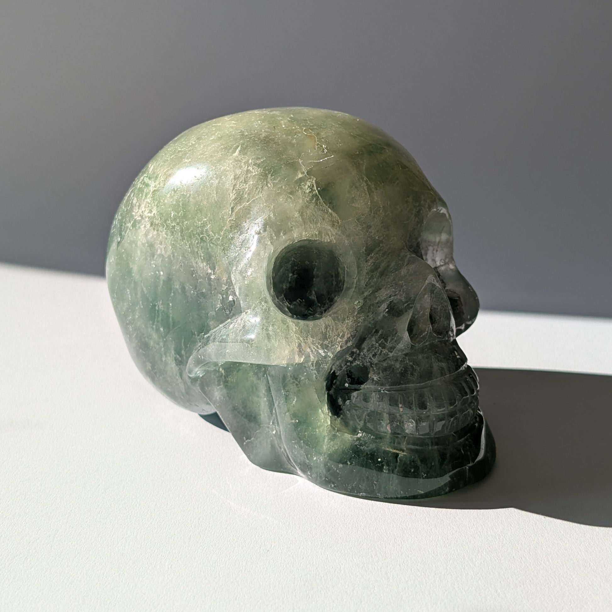 Großer Kristallschädel "Gulkar" (fast 2kg) aus leuchtend grünem Fluorit, seitlich beleuchtet.