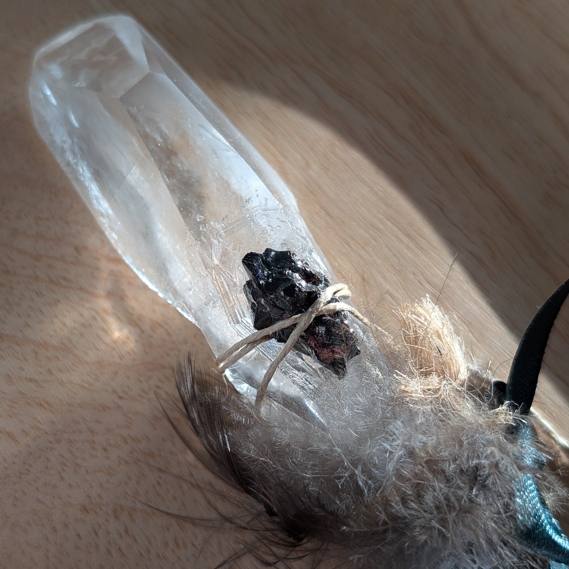 Handgefertigter Zauberstab mit großer Bergkristall-Spitze, verziert mit Federn, Kyanit und einem grünem Band.