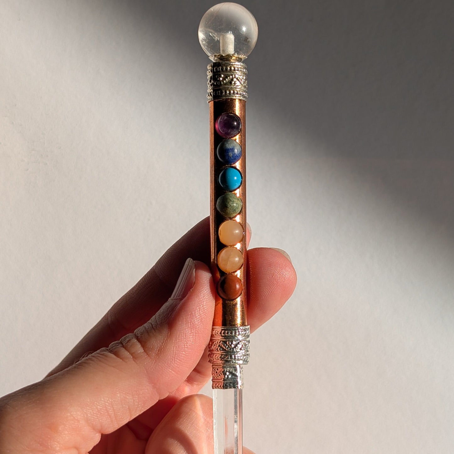 Handgehaltener Chakra-Stab aus leuchtendem Kupfer mit sieben farbigen Edelsteinen und Bergkristall-Spitzen.