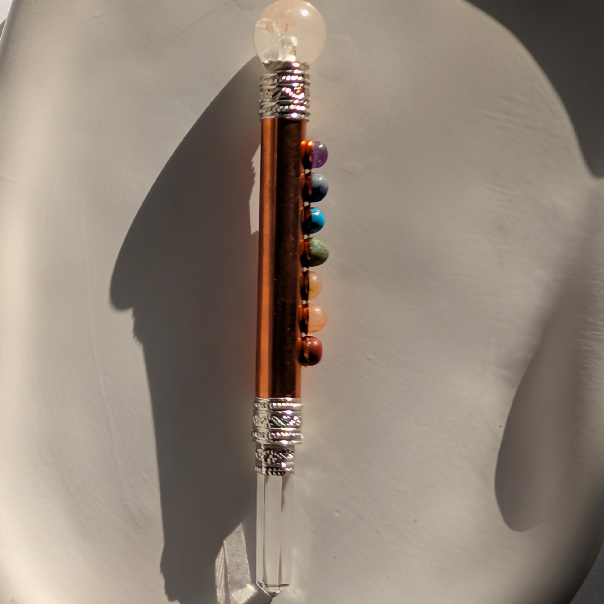 Handgehaltener Chakra-Stab aus leuchtendem Kupfer mit sieben farbigen Edelsteinen und Bergkristall-Spitzen.