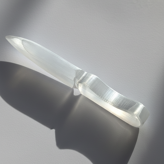 Handgeschliffenes Ritualmesser aus weißem, lichtdurchlässigem Selenit auf hellem Untergrund.