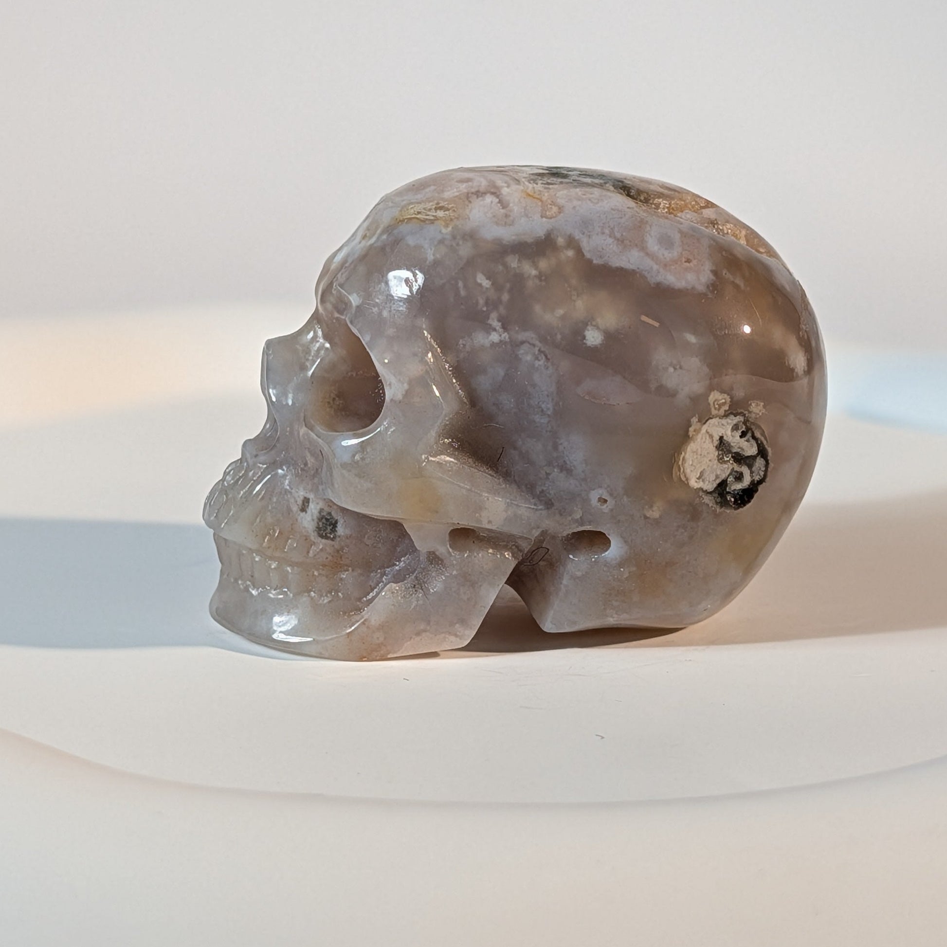 Handgeschnitzter Kristallschädel Jeweler aus echtem Blumenachat, 85 Gramm schwer, mit weißen Blüten-Einschlüssen und kleiner, natürlicher Kristallhöhle.