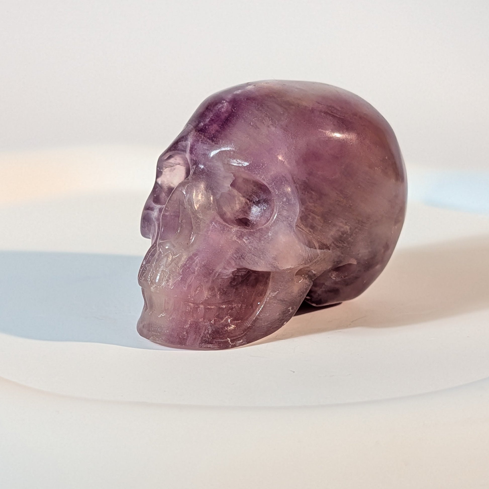 Handgeschnitzter Kristallschädel Katras aus echtem, violettem Fluorit, 97 Gramm schwer, mit markanter, gerader Farbbänderung für Konzentration und Fokus.