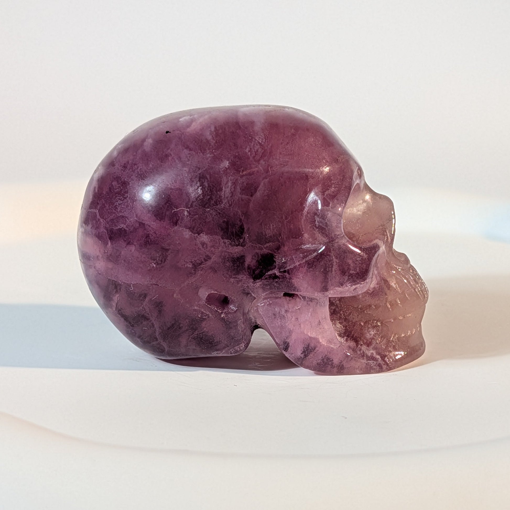 Handgeschnitzter Kristallschädel Katras aus echtem, violettem Fluorit, 97 Gramm schwer, mit markanter, gerader Farbbänderung für Konzentration und Fokus.