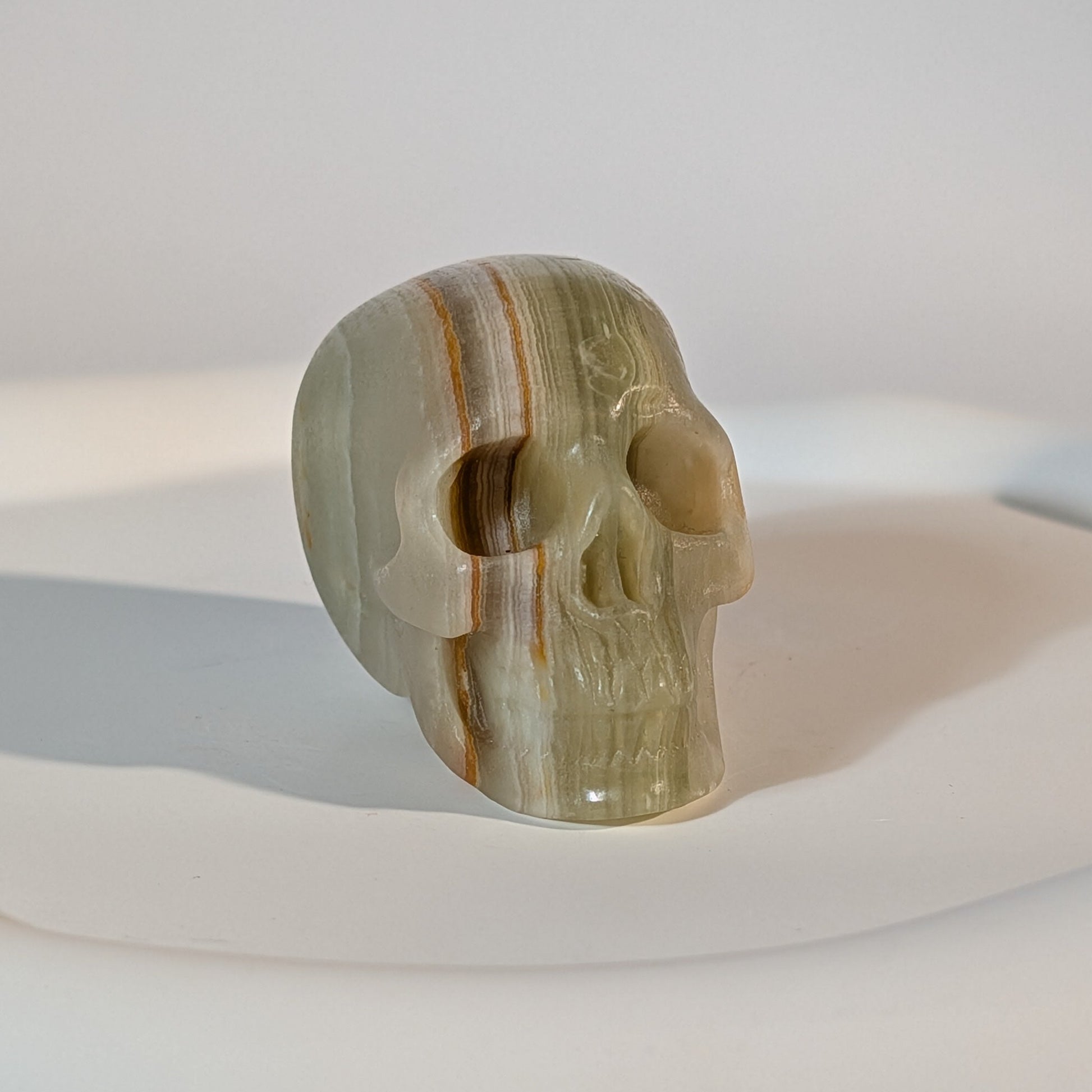 Handgeschnitzter Kristallschädel Kerwen aus grün-braunem Bänder-Aragonit (Grüner Onyx), 78 Gramm schwer, für emotionale Balance und Geduld.