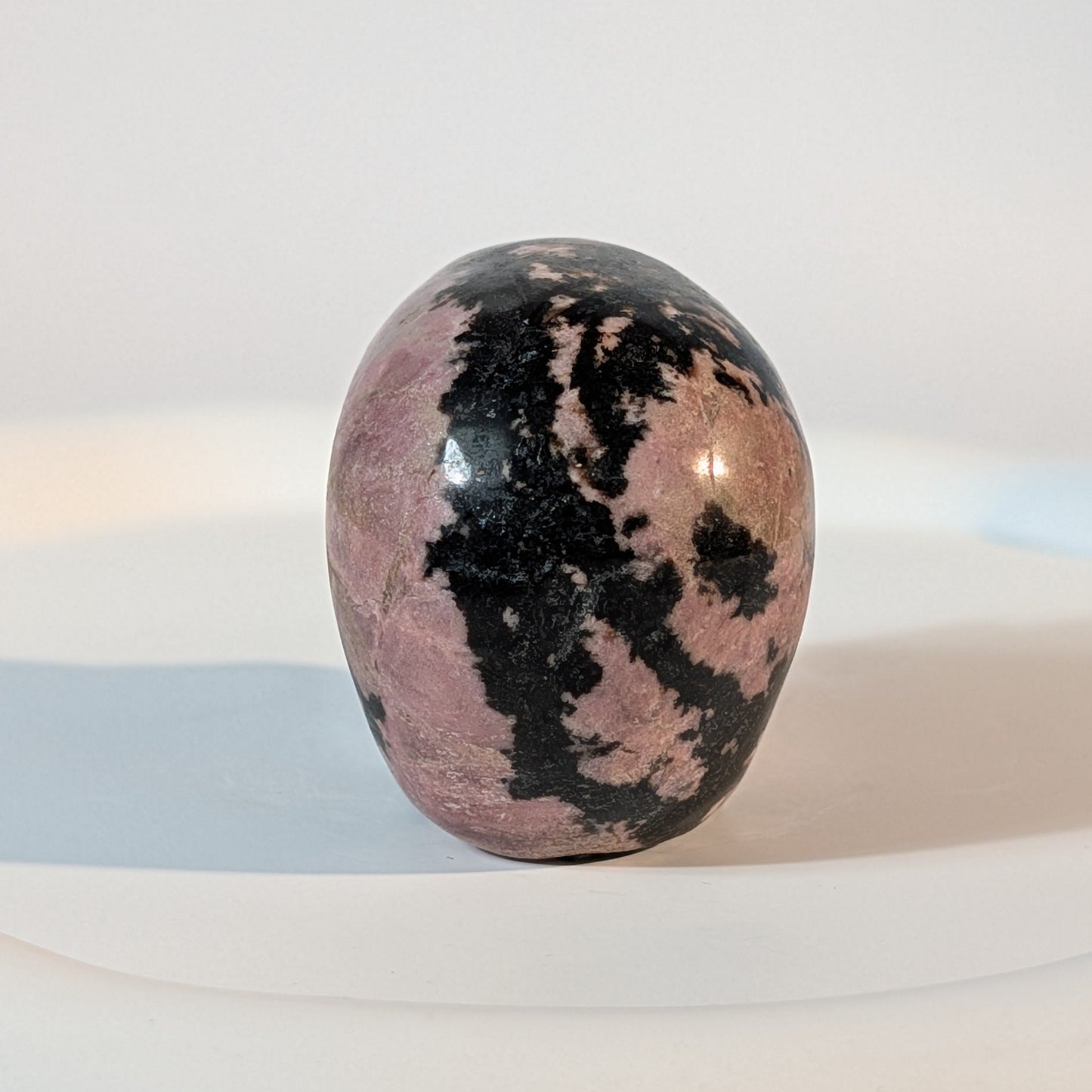 Handgeschnitzter Kristallschädel Sariel aus echtem Rhodonit, 114 Gramm schwer, mit markanter rosa-schwarzer Maserung für emotionale Heilung und Erdung.