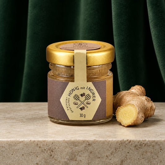 Honig mit Ingwer 30 g im kleinen Glas mit Golddeckel, daneben eine Ingwerknolle