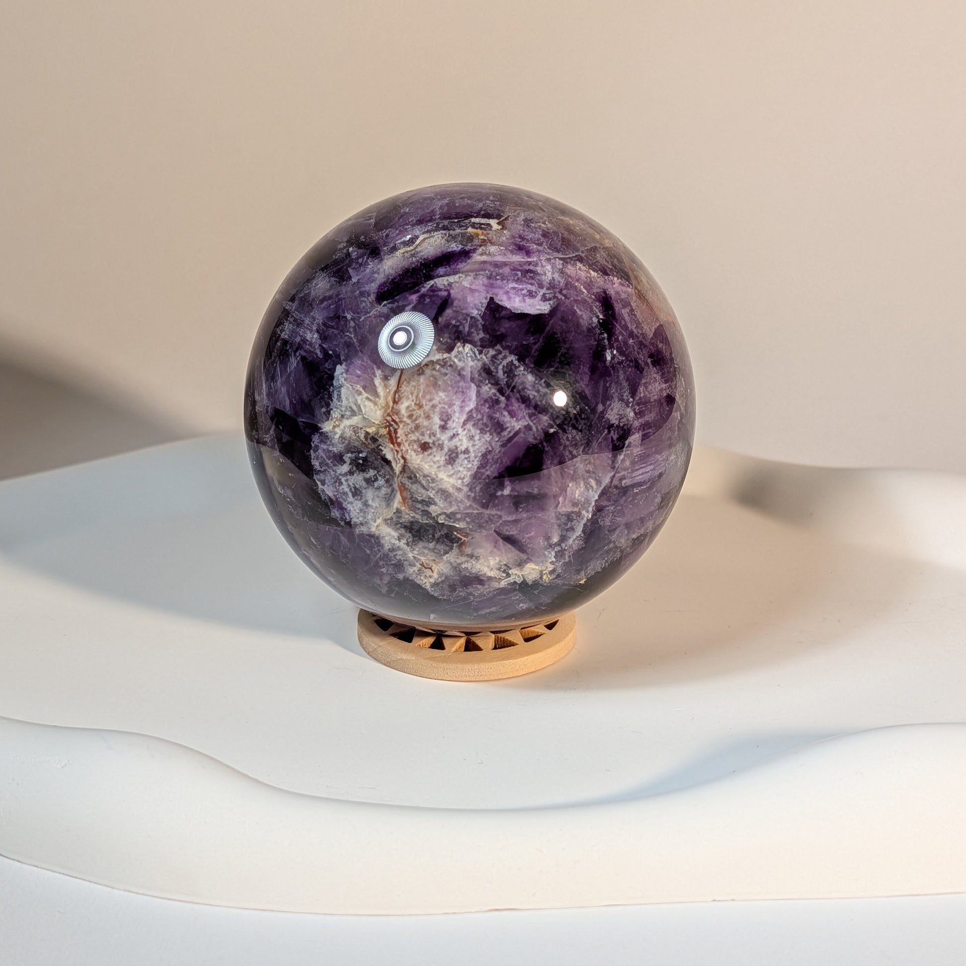 Chevron-Amethyst Kristallkugel K6 458g - Ansicht mit Holzuntersetzer