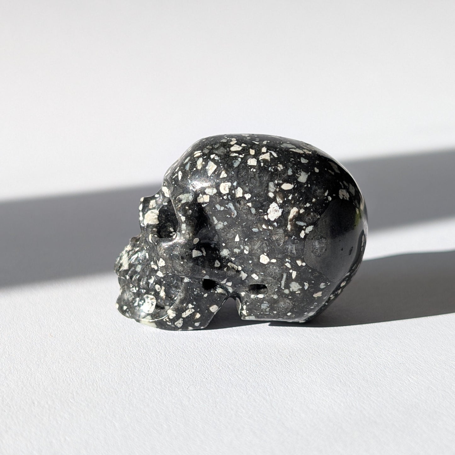 Kleiner Kristallschädel "Blyss" (87g) aus dunkelgrauem Gabbro (Mystic Merlinite) mit hellen Sprenkeln.