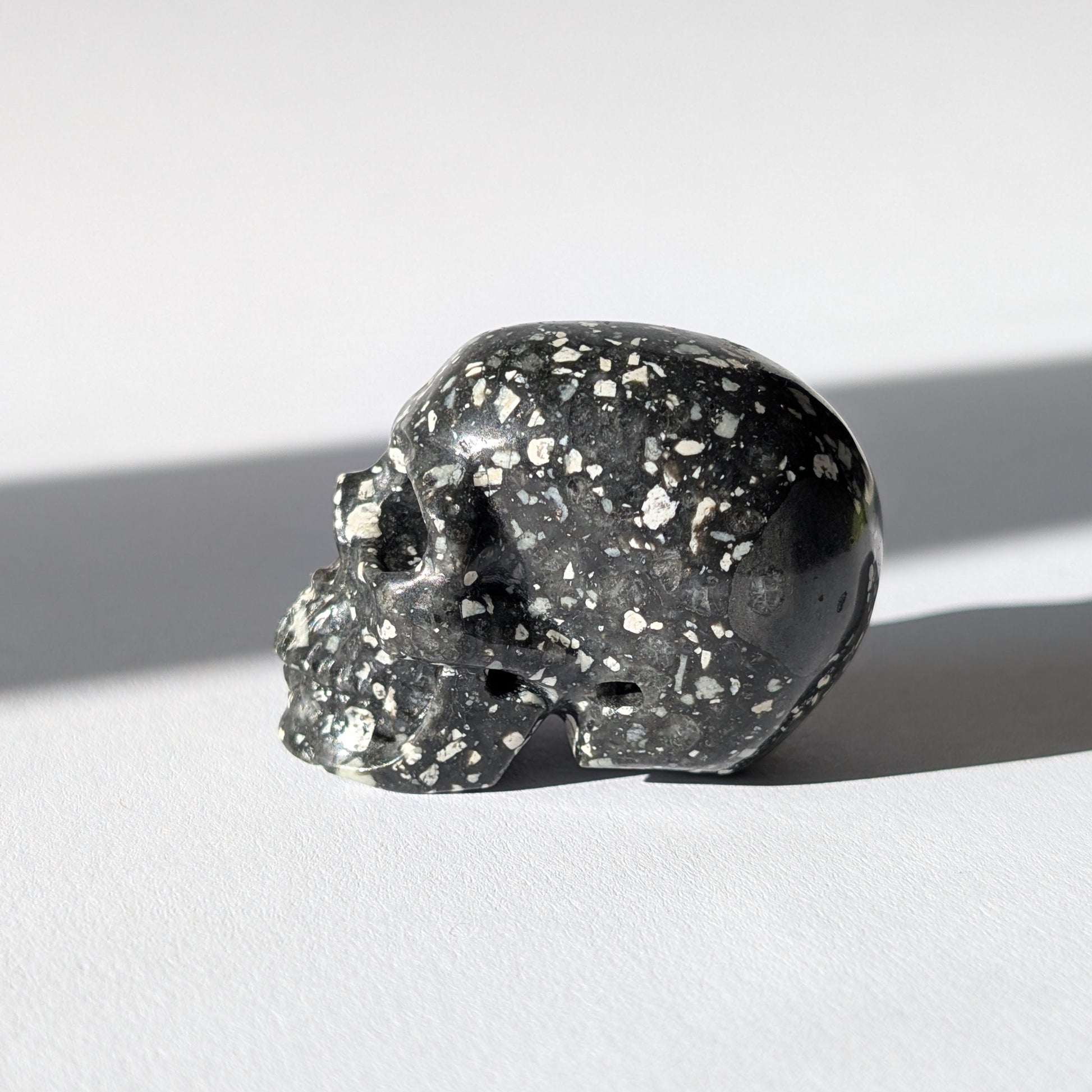 Kleiner Kristallschädel "Blyss" (87g) aus dunkelgrauem Gabbro (Mystic Merlinite) mit hellen Sprenkeln.