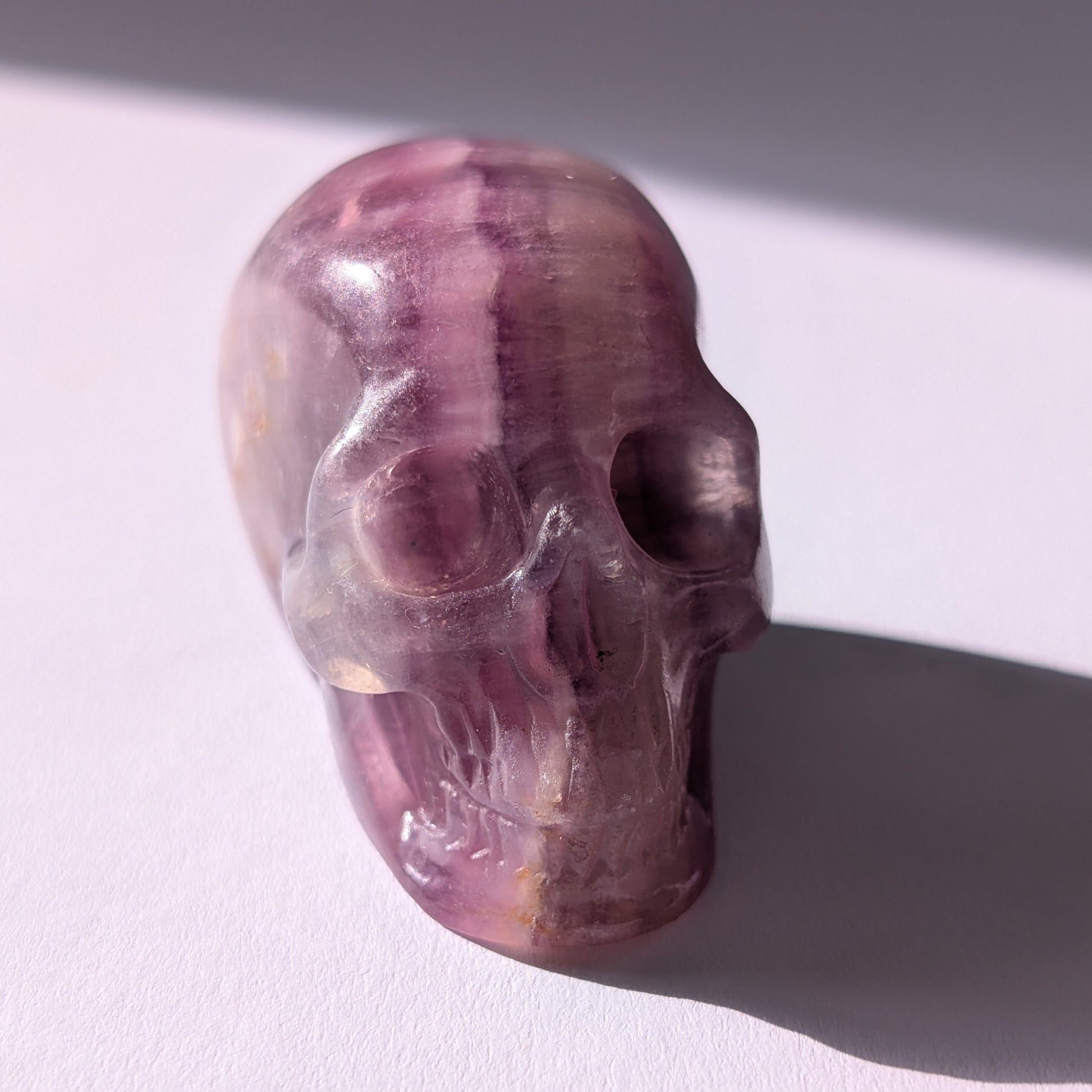 Kleiner Kristallschädel "Boron" (99g) aus klar gebändertem violett-weißem Fluorit.