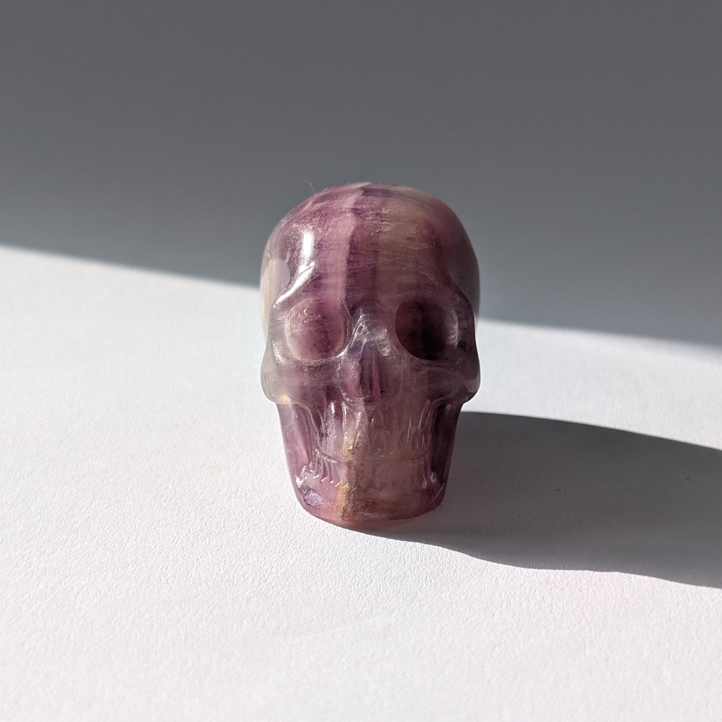 Kleiner Kristallschädel "Boron" (99g) aus klar gebändertem violett-weißem Fluorit.